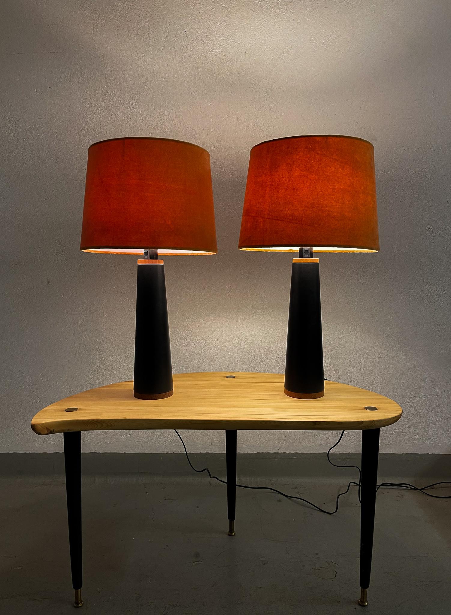 Pair of table lamps manufactured in Sweden and produced by famous Luxus. They are made in black synthetic leather with stiches around a teak base. 

All new quality shades produced in Sweden.

Nice vintage condition. Rewired

Dimensions: Height