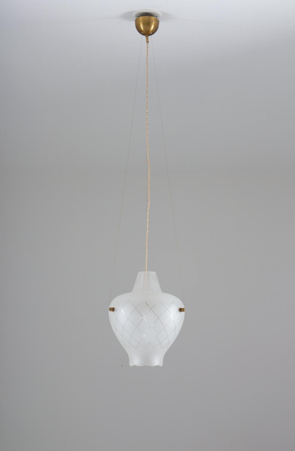 Add a touch of sophistication and style to your home with this elegant pendant light, produced in Sweden during the Swedish modern era. The brass and blasted glass construction creates a sleek and modern look, while the frosted glass diffuses the