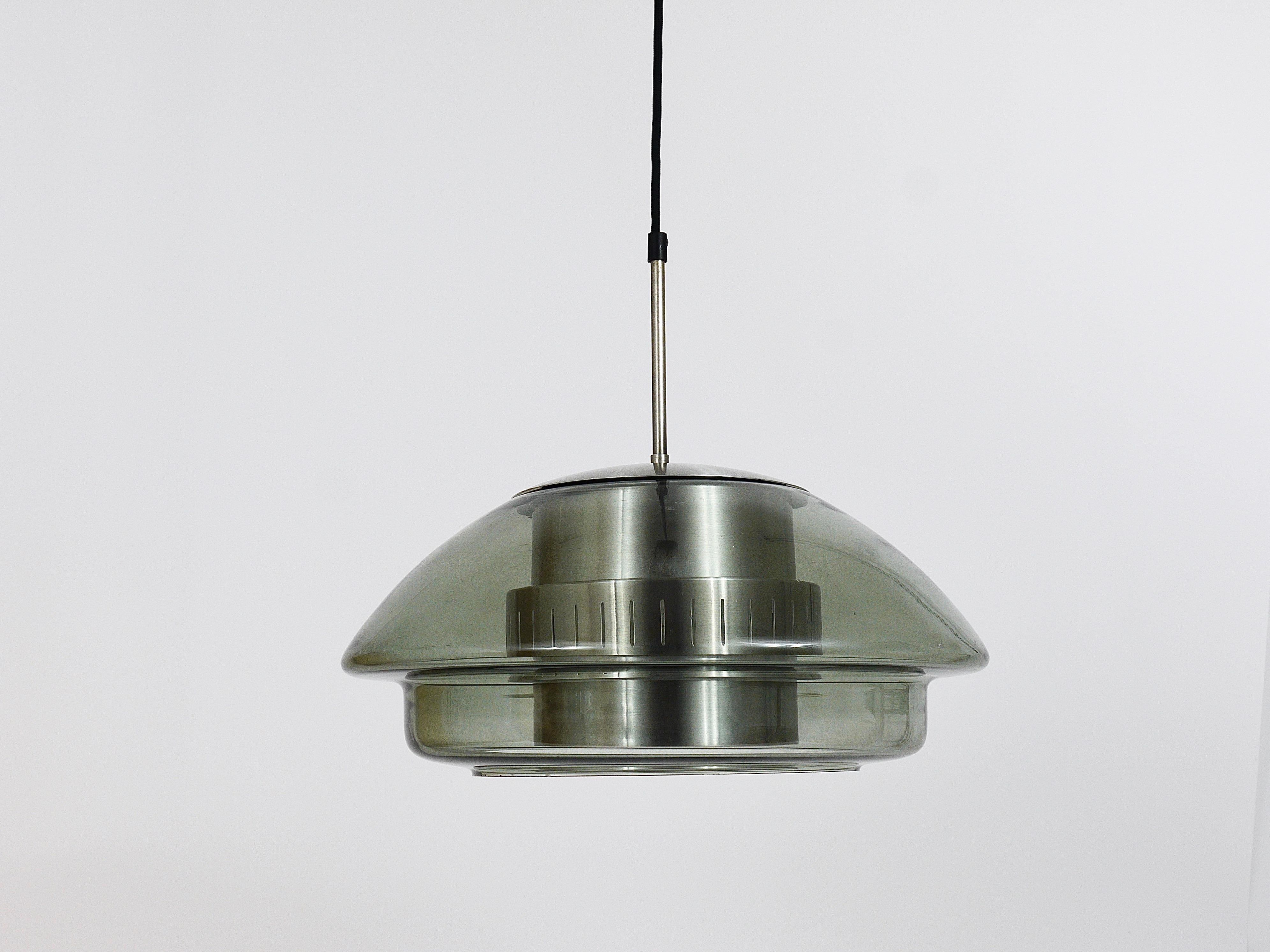 A beautiful Danish Midcentury pendant light from the 1960s. Made of silver aluminum with a nice round lampshade, made of grey smoked glass. In the style of Jo Hammerborg / Fog & Mørup. In good condition with age-related patina. Makes a wonderful