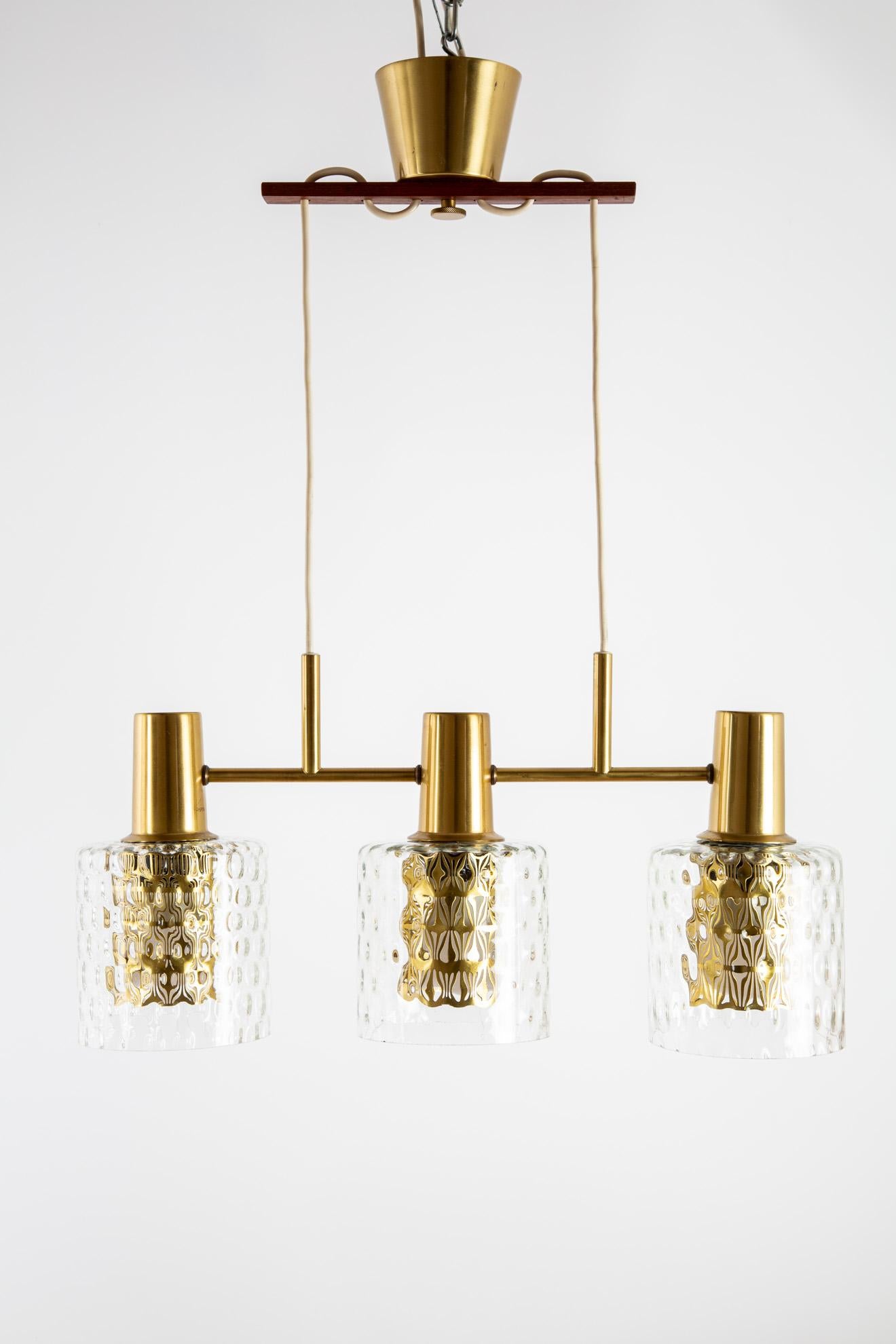 Hans Agne Jakobsson. A Scandinavian Modern pendant lamp. The frame system is of brass. The shades are of bubbled glass. Total width is 52 cm and height is 23 cm. Inclusive a brass ceiling piece.