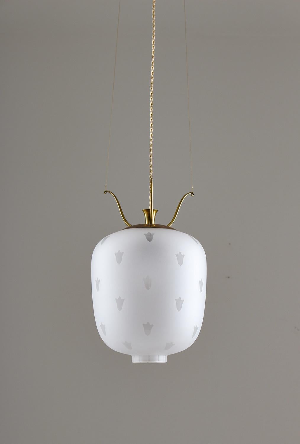 Elegant pair of pendants in brass and blasted glass produced in Sweden. The frosted glass gives a beautiful and soft light and the brass parts have a soft natural patina. The lamps hang from three twisted brass wires that are fixed on the top brass