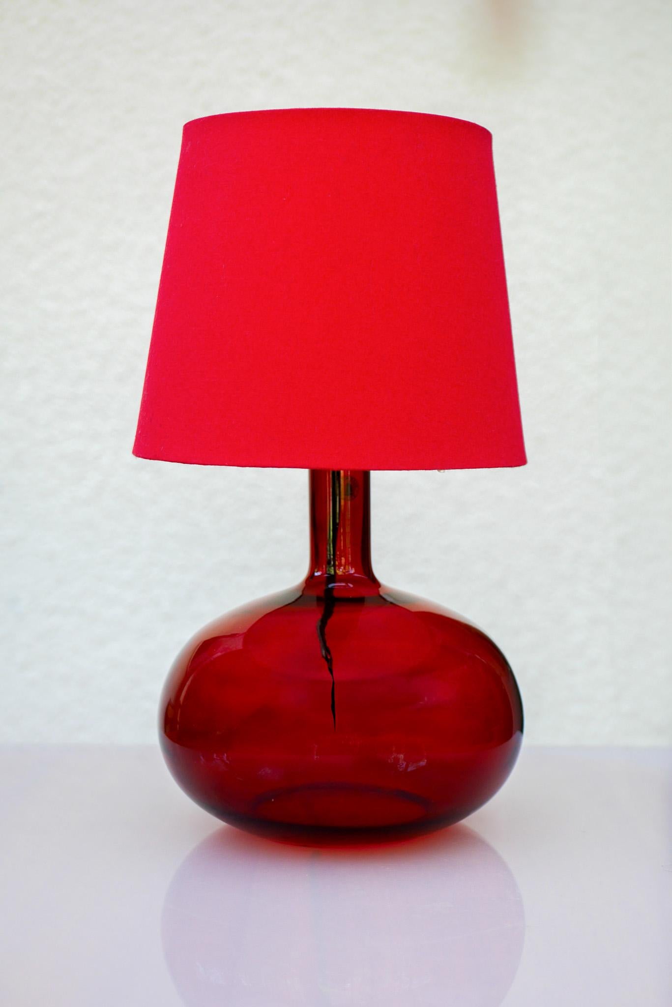 A striking vintage table lamp designed by renowned Swedish designer Anne Nilsson for IKEA in the early 1990s. This medium-sized lamp features a vibrant red blown glass base, a hallmark of Nilsson’s bold yet elegant design sensibility. Its rounded