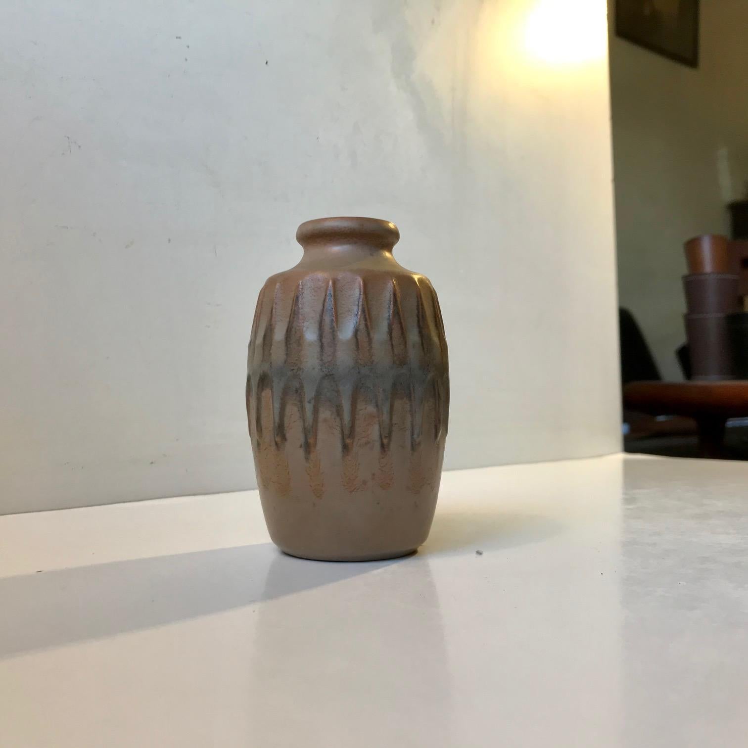 Vase en céramique aux glaçures de camouflage subtilement/semi-matées conçu par le céramiste autrichien Günther Praschak qui a travaillé à knabstrup au Danemark de 1964 à 1969. Il comporte un décor central en relief représentant un diagramme en forme