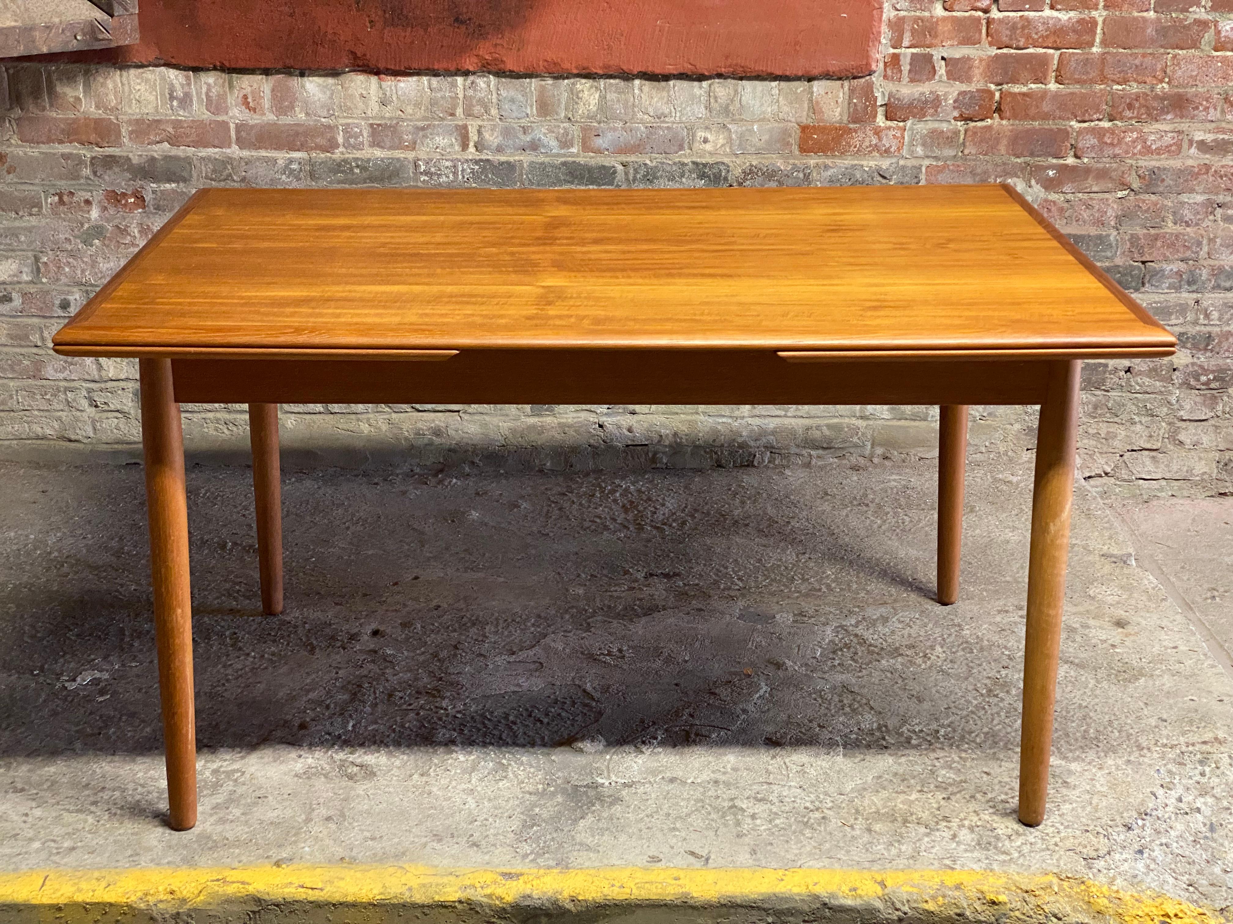 Scandinavian teak dining table. Circa 1960-70. Featuring rectangular top, removable legs for flat pack shipping, two hidden draw leaf extensions, beautifully figured teak veneer top with mitered edge joinery. A wonderful space saving Scandinavian