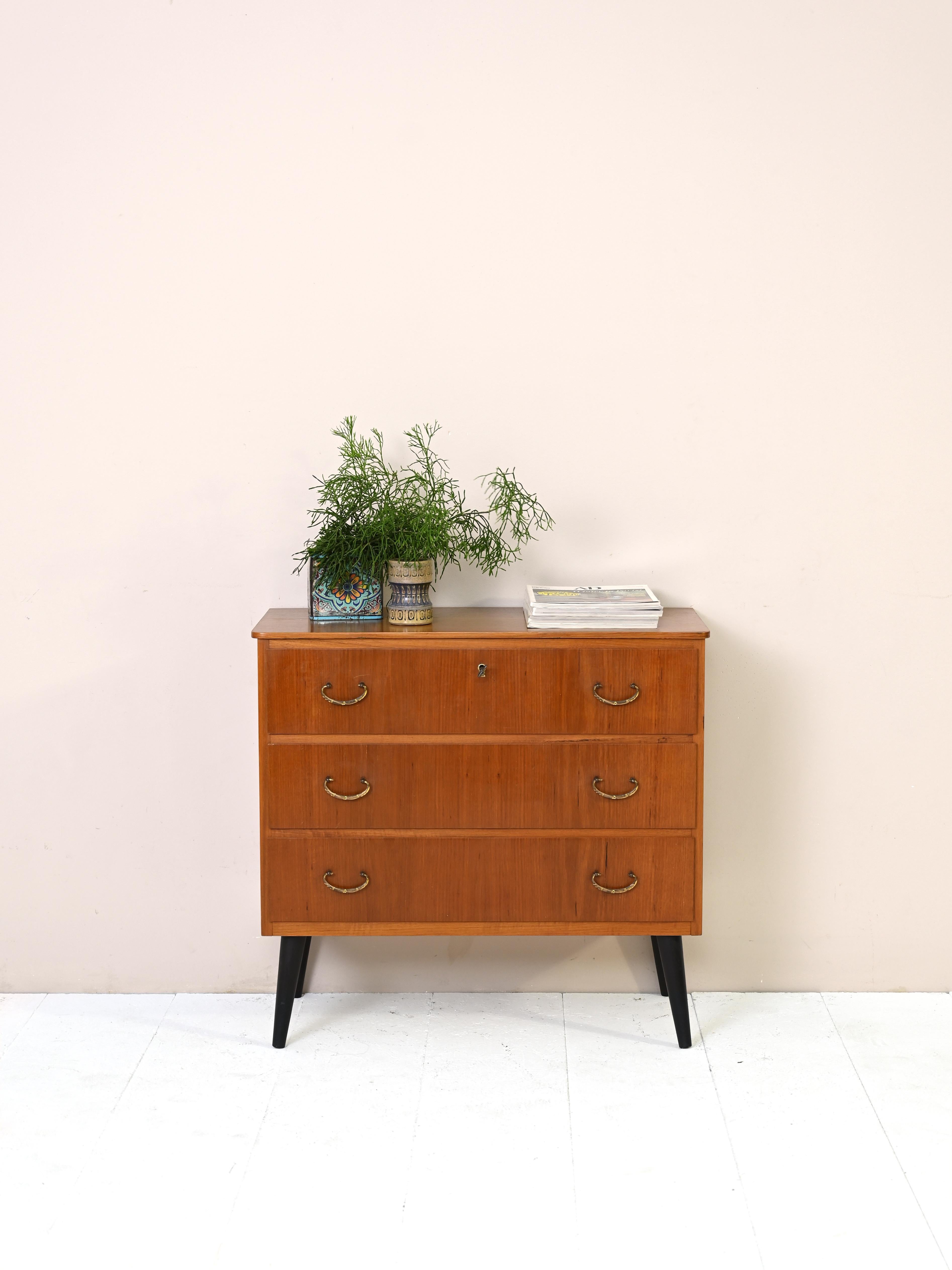 Petit meuble vintage à trois tiroirs, dont le premier est muni d'une serrure.
Agrémenté de poignées en métal doré et de pieds en bois peints en noir.
Cette commode peut être utilisée dans n'importe quelle pièce de la maison. Elle est également