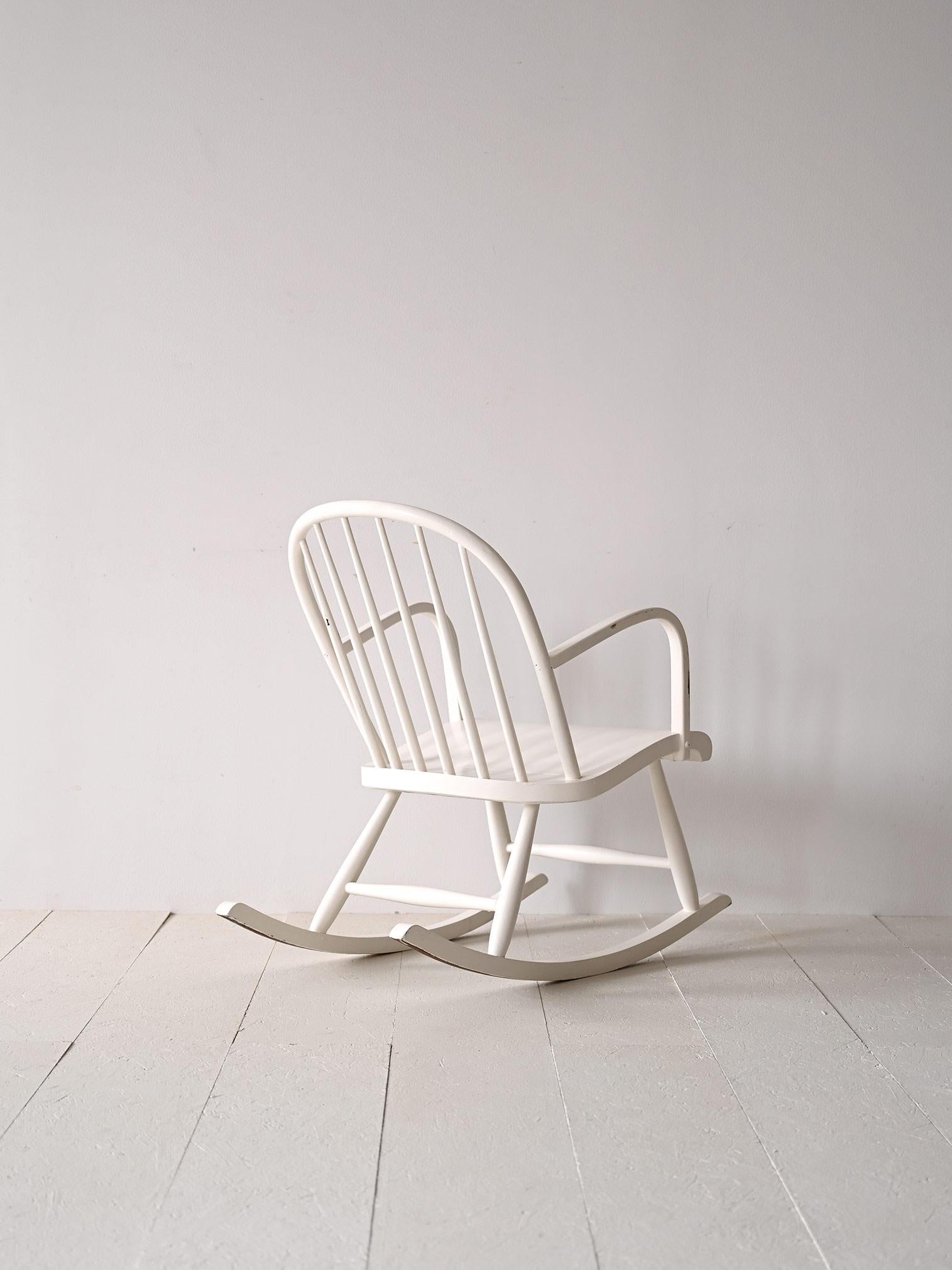 Scandinavian rocking chair made of wood painted white.

A piece of furniture that refers to the typical shape of classic Scandinavian wooden 'Pinstolar' chairs.
In addition to the backrest, which consists of wooden stems, there is a seat with