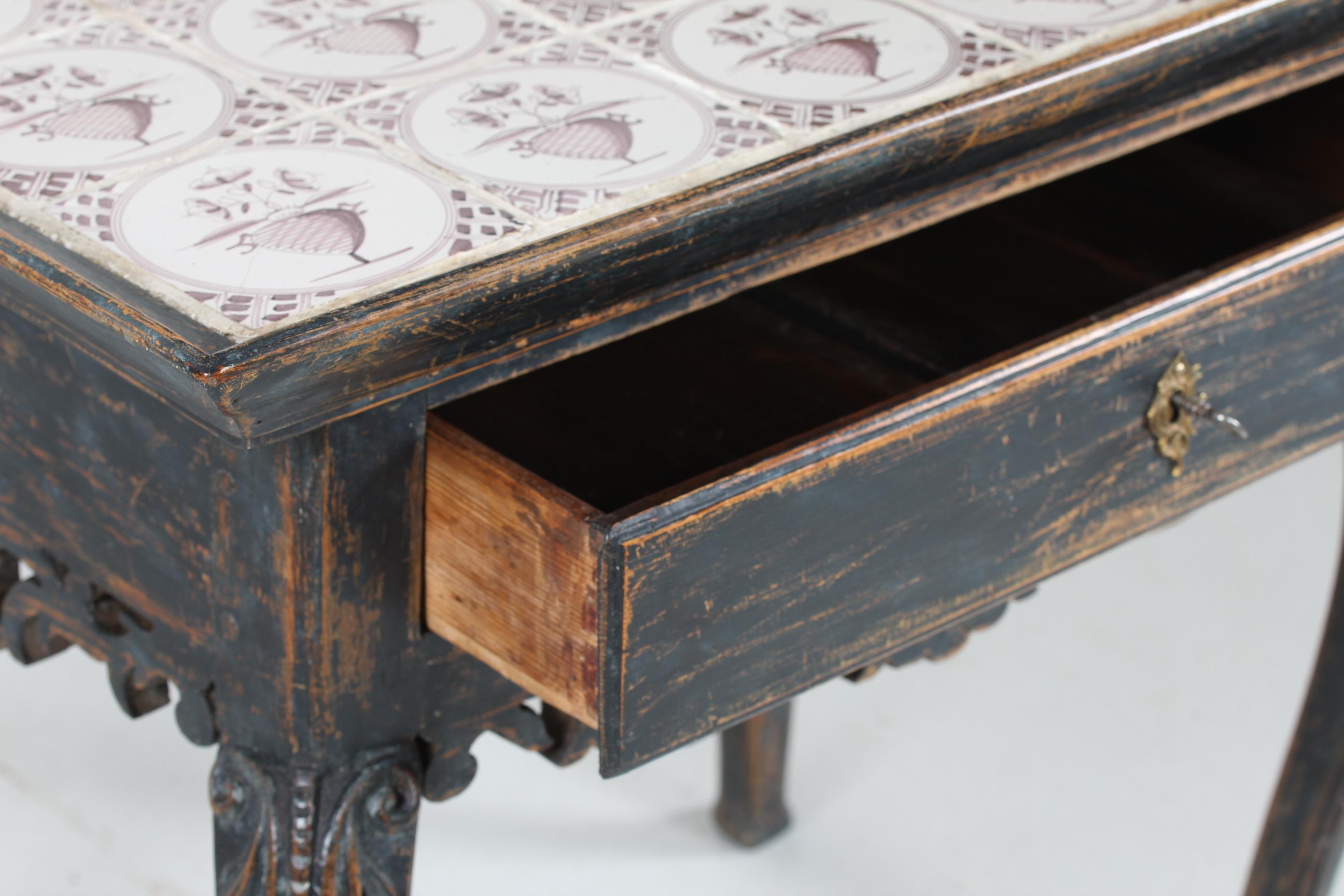 Danish or Swedish Rococo table with drawer with hand carved ormaments on the legs
It's made of solid wood with dark blue/green paint with patina.
The Tiles on the top are made in Holland and hand painted in 19th century.