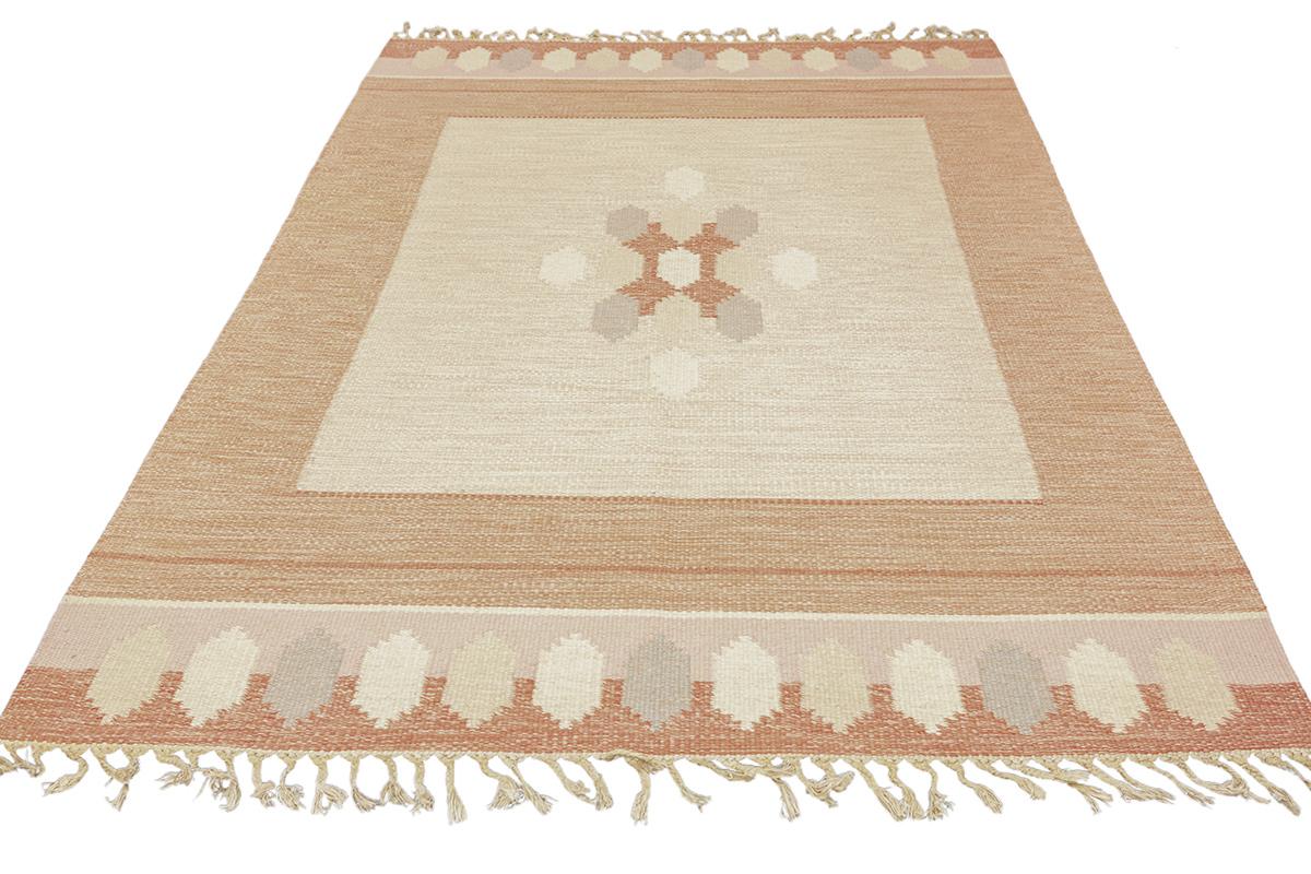 Dieser exquisite skandinavische Teppich Röllakan ist eine Symphonie aus warmen, erdigen Tönen und eleganten Mustern, die meisterhaft verarbeitet sind und jedem Raum einen Hauch von nordischem Charme verleihen. Das Design dieses Teppichs, der mit