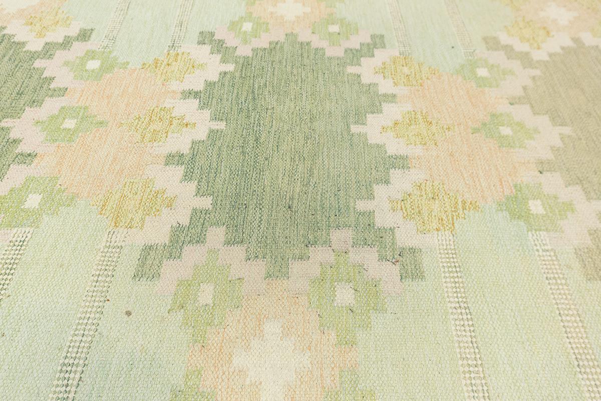 This Scandinavian Rollakan Rug, measuring 165 × 237 cm, is a stunning example of Nordic craftsmanship, blending traditional weaving techniques with a soft, harmonious color palette. Rollakan rugs are highly regarded in Scandinavian culture for their
