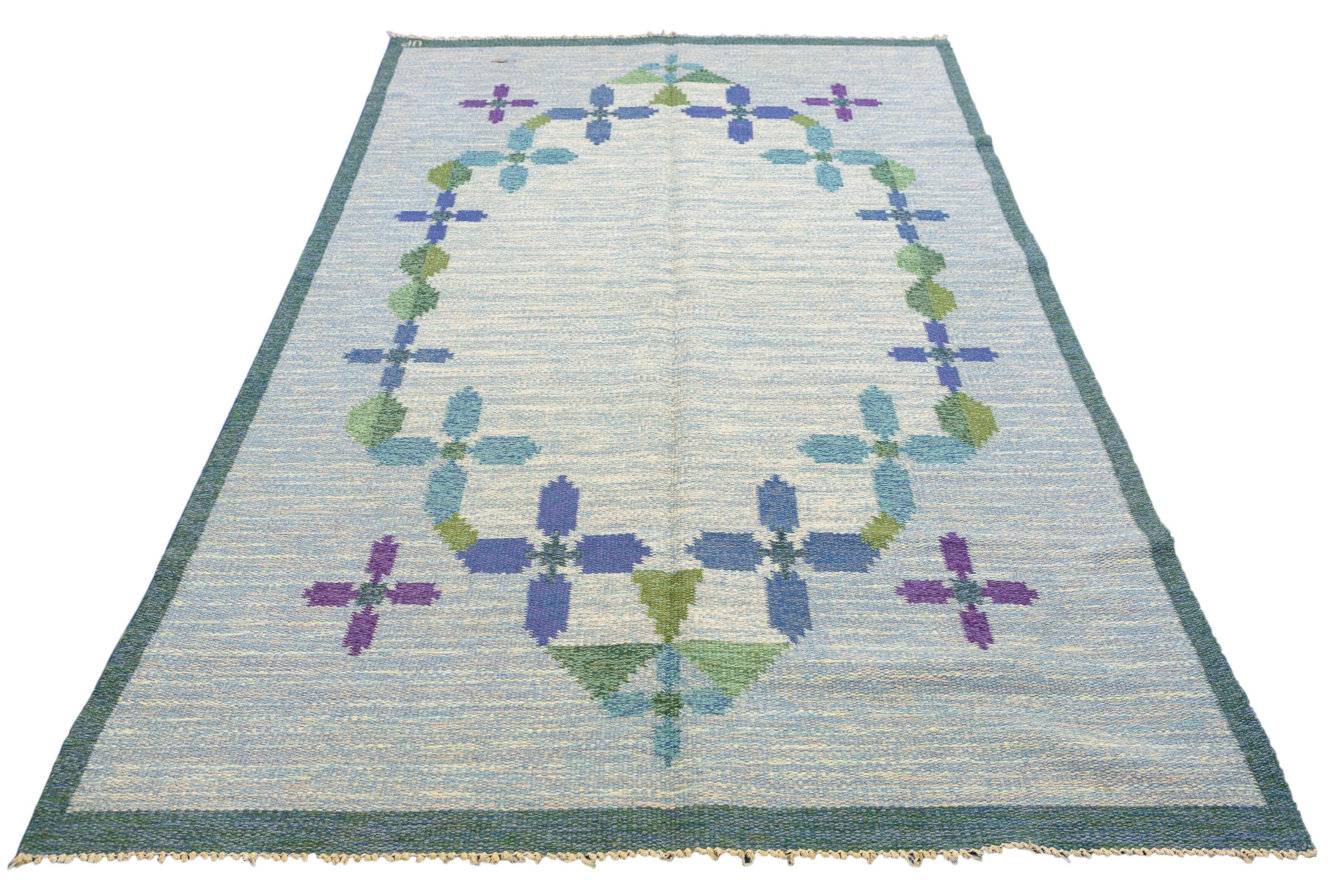 This is a truly unique Rollakan Swedish rug, featuring a soft and soothing background color, adorned with a captivating combination of green, purple, and blue hues. This remarkable piece exemplifies the perfect harmony of artistic design and