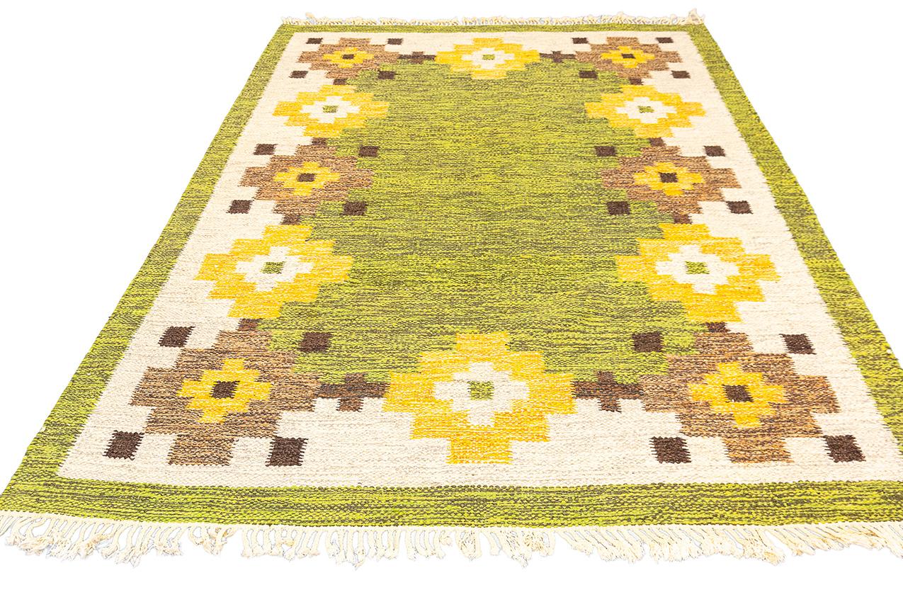 The Rollakan Swedish Green Field Signed IS is a great quality  piece that exudes uniqueness and special charm. With its geometric design and a captivating range of colors, including beige, green, brown, and yellow, this Rollakan stands out as a true