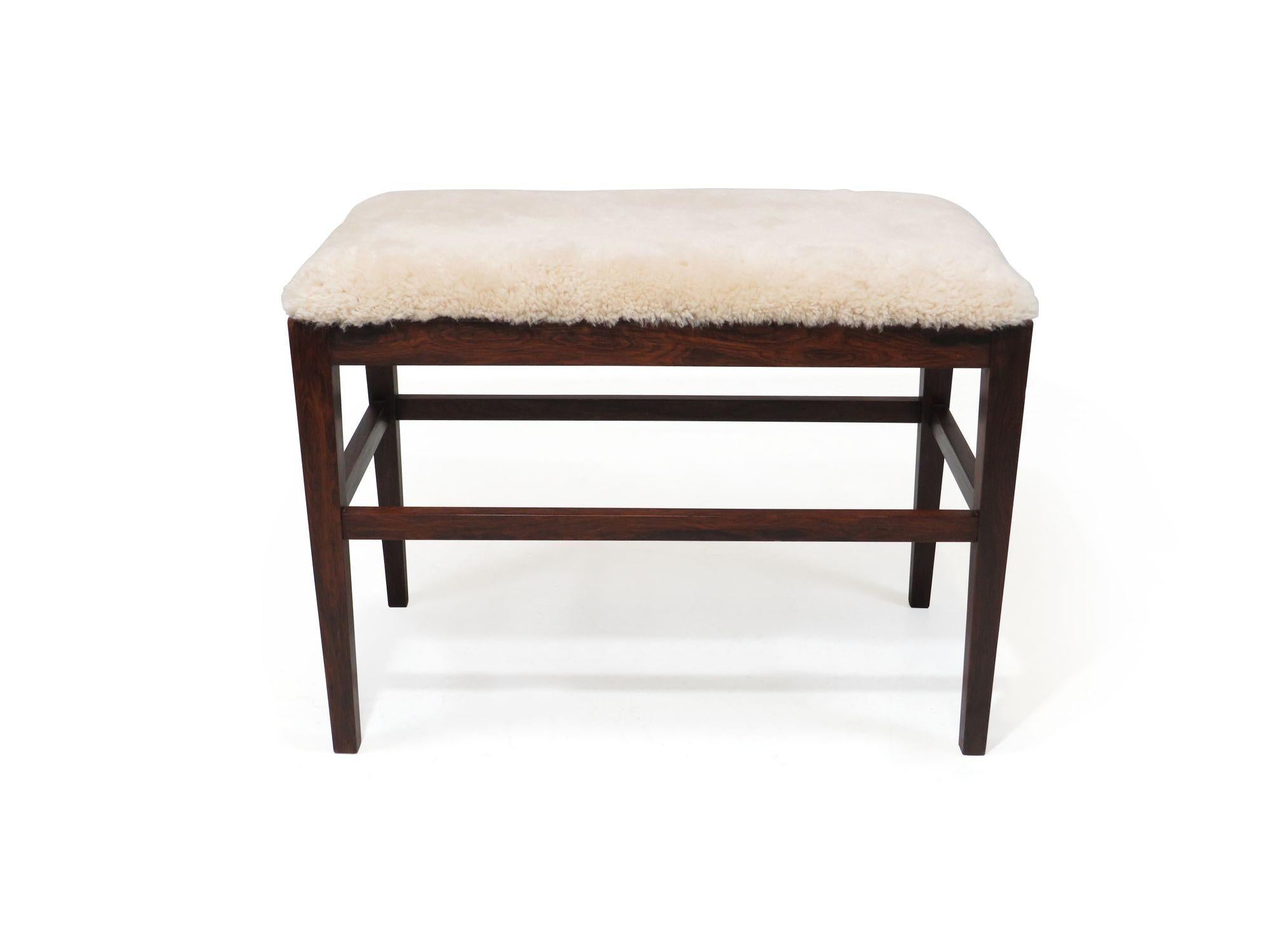 Rosewood bench with elegant tapered legs with cross stretchers, crafted of solid Brazilian Rosewood, and newly upholstered a natural shearling over new foam.
 