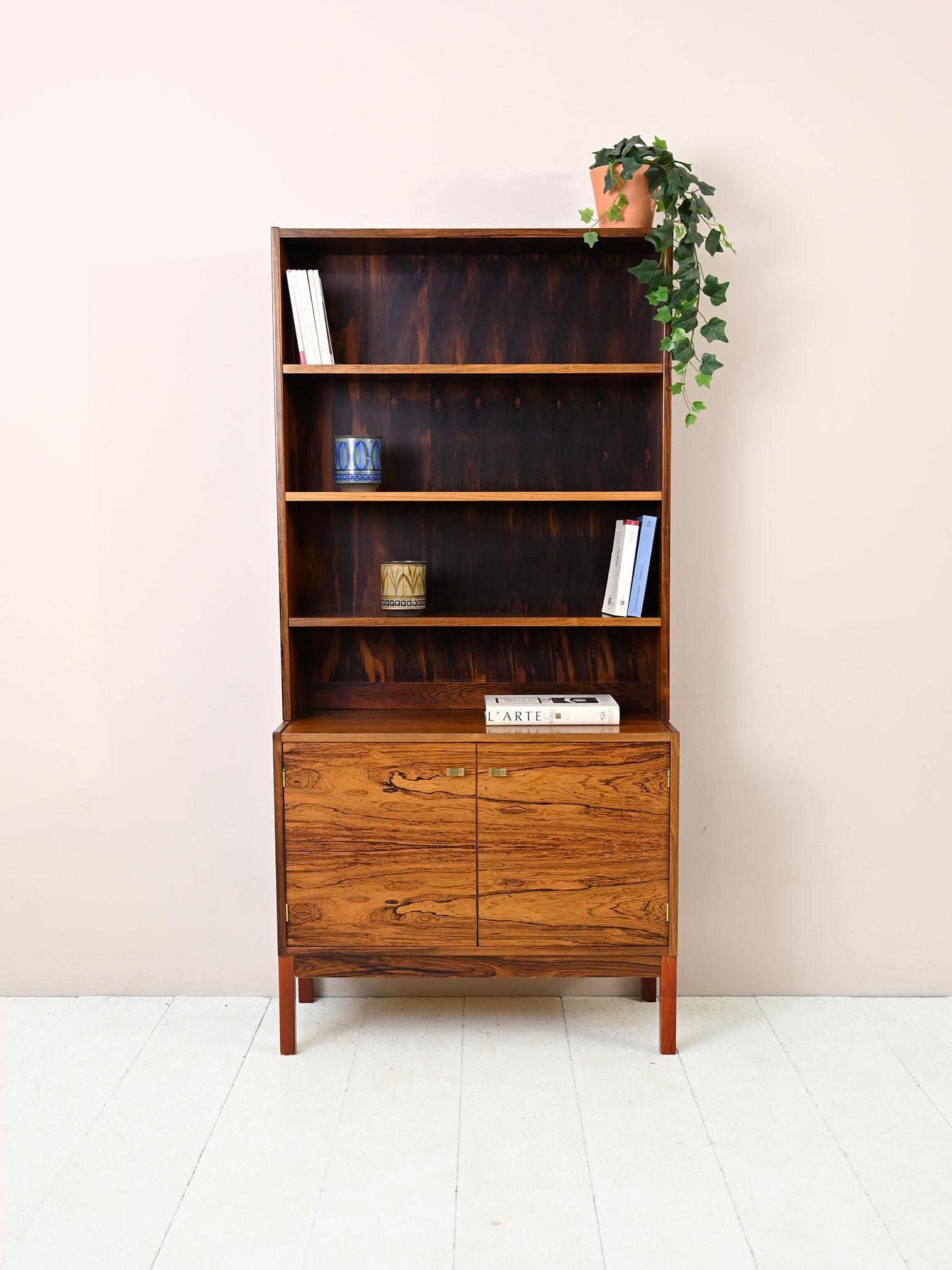 Swedish 1960s bookcase with storage compartment.

A classically elegant piece of furniture consisting of a cabinet with hinged doors on which rests a frame equipped with three adjustable-height shelves. The gilded metal door handles give it a