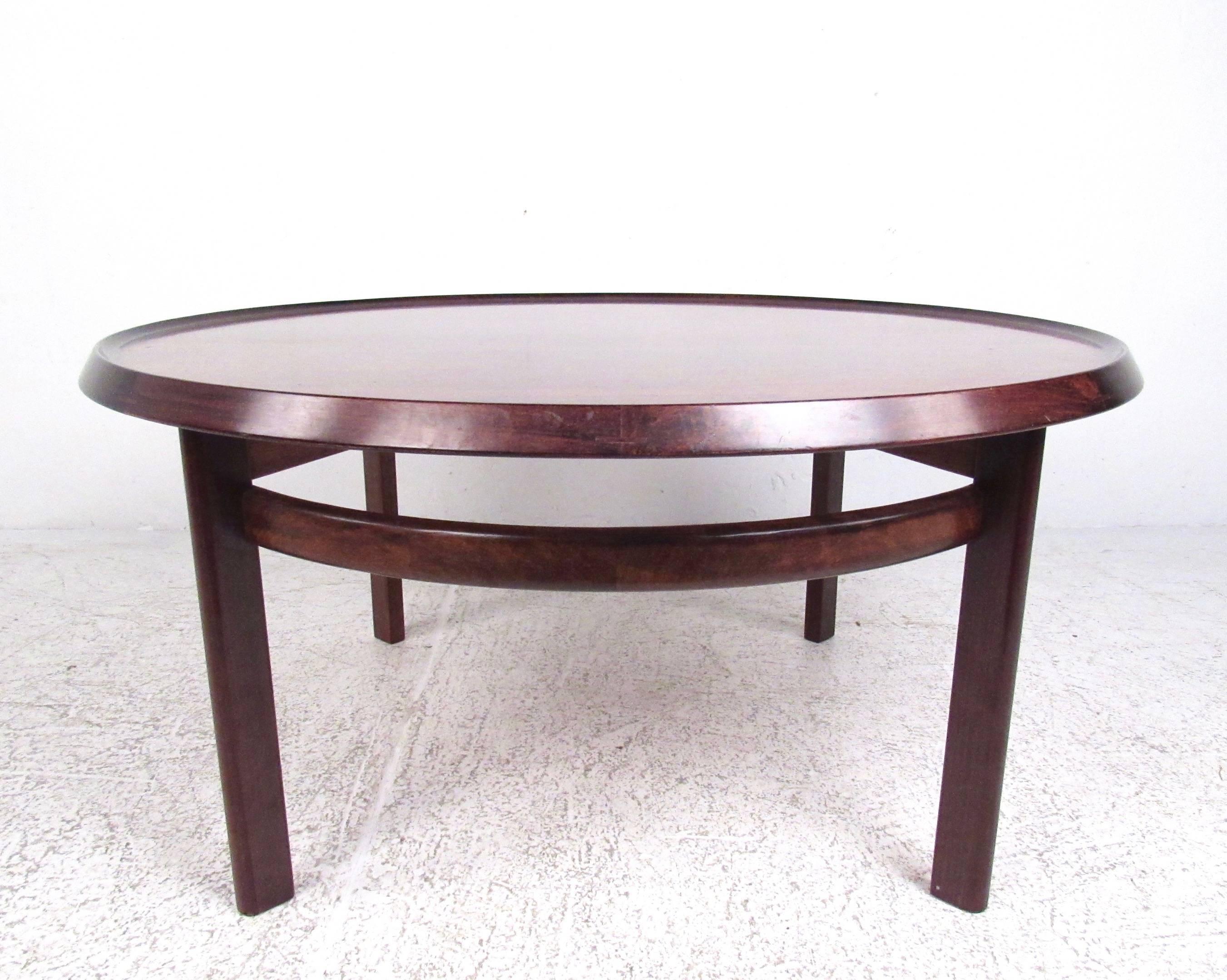 This stylish Mid-Century Modern coffee table features the Scandinavian Modern design of Haug Snekkeri for Bruksbo. Rich vintage rosewood finish, sturdy vintage construction, and unique raised edge all add to the appeal of this circular cocktail