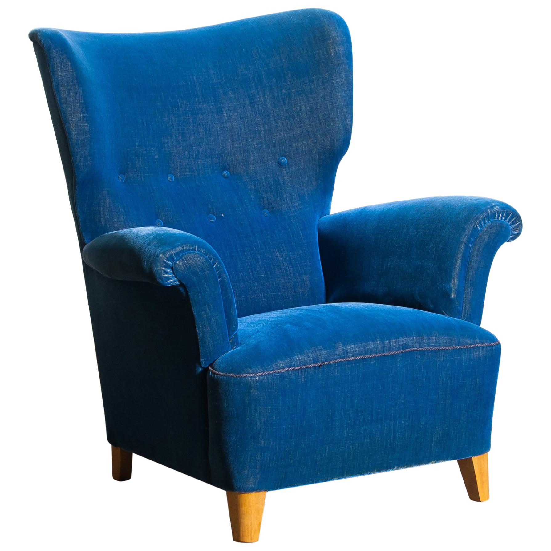 Beautiful robust 1930-1940 wingback chair in royal blue velvet and beech from Sweden, 1940s. This wingback chair is typical for early midcentury Scandinavian design.
The somewhat thin velvet gives the chair a beautiful character. Padding/springs