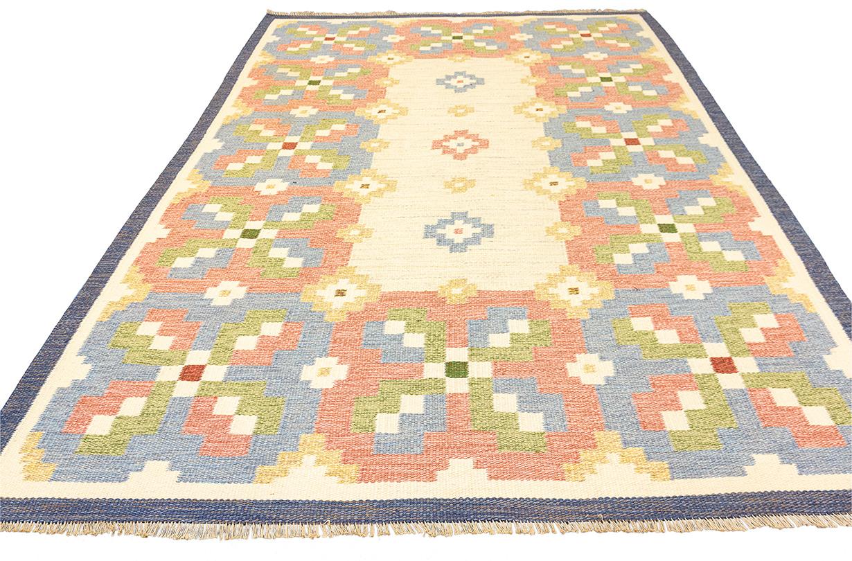 Questo tappeto scandinavo Rollakan, che misura 241 × 170 cm, è un bellissimo esempio di tessitura tradizionale svedese che unisce la funzionalità all'estetica dell'arte popolare. I tappeti Rollakan sono noti per la loro trama piatta e spesso