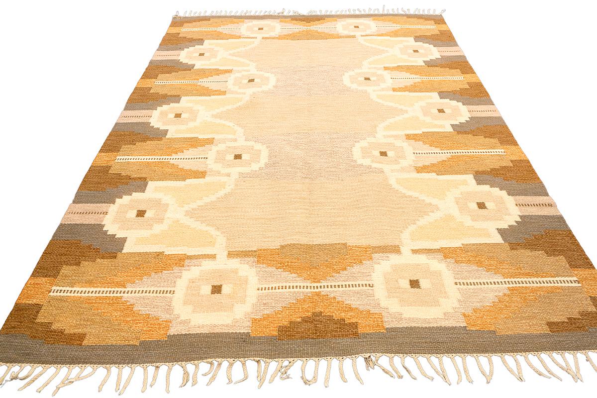 This Scandinavian Rollakan rug, measuring 280 × 193 cm, is a beautifully handwoven textile that embodies the essence of Nordic design. The rug features a sophisticated geometric pattern with symmetrical motifs, making it a perfect blend of modern