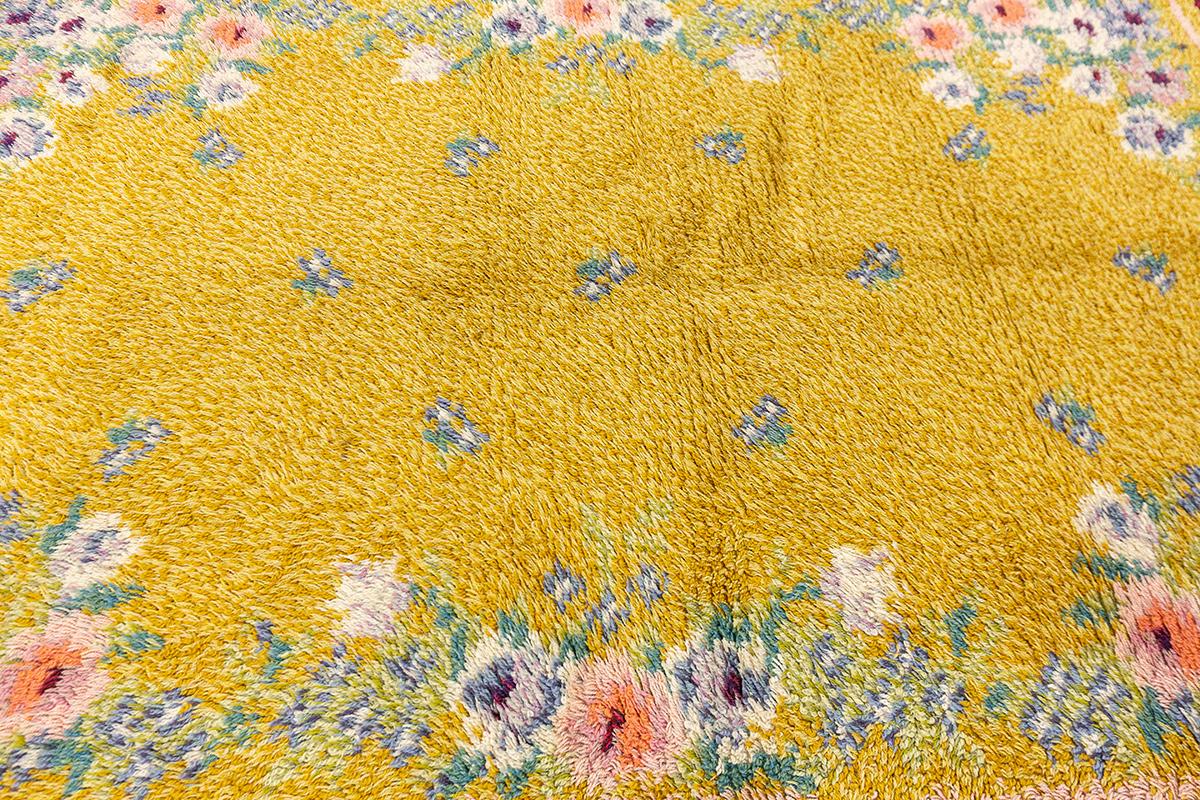 Questo tappeto scandinavo Rya, che misura 207 x 146 cm, incarna magnificamente l'artigianato nordico con il suo lussuoso e spesso vello e il suo calore invitante. Ammobiliato con un vivace campo giallo senape, questo tappeto presenta un bordo