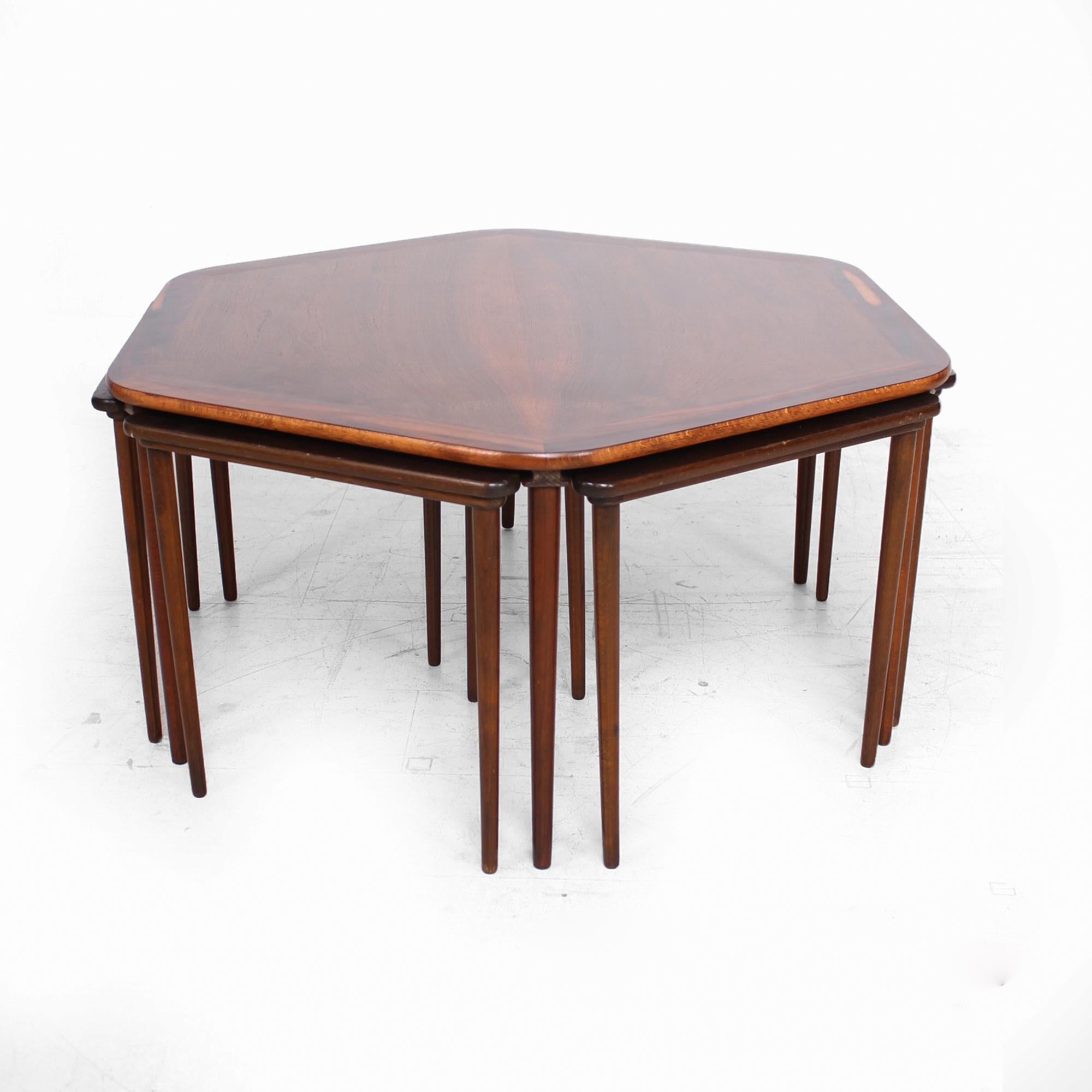 AMBIANIC offering:
Fantastic set of six rosewood nesting tables under a hexagonal rosewood coffee table. 
Made in Denmark 1950s
The coffee table is hexagonal with 6 nesting tables. Set includes 7 pieces.
Overall dimensions: 17.38 tall x 34.13 depth