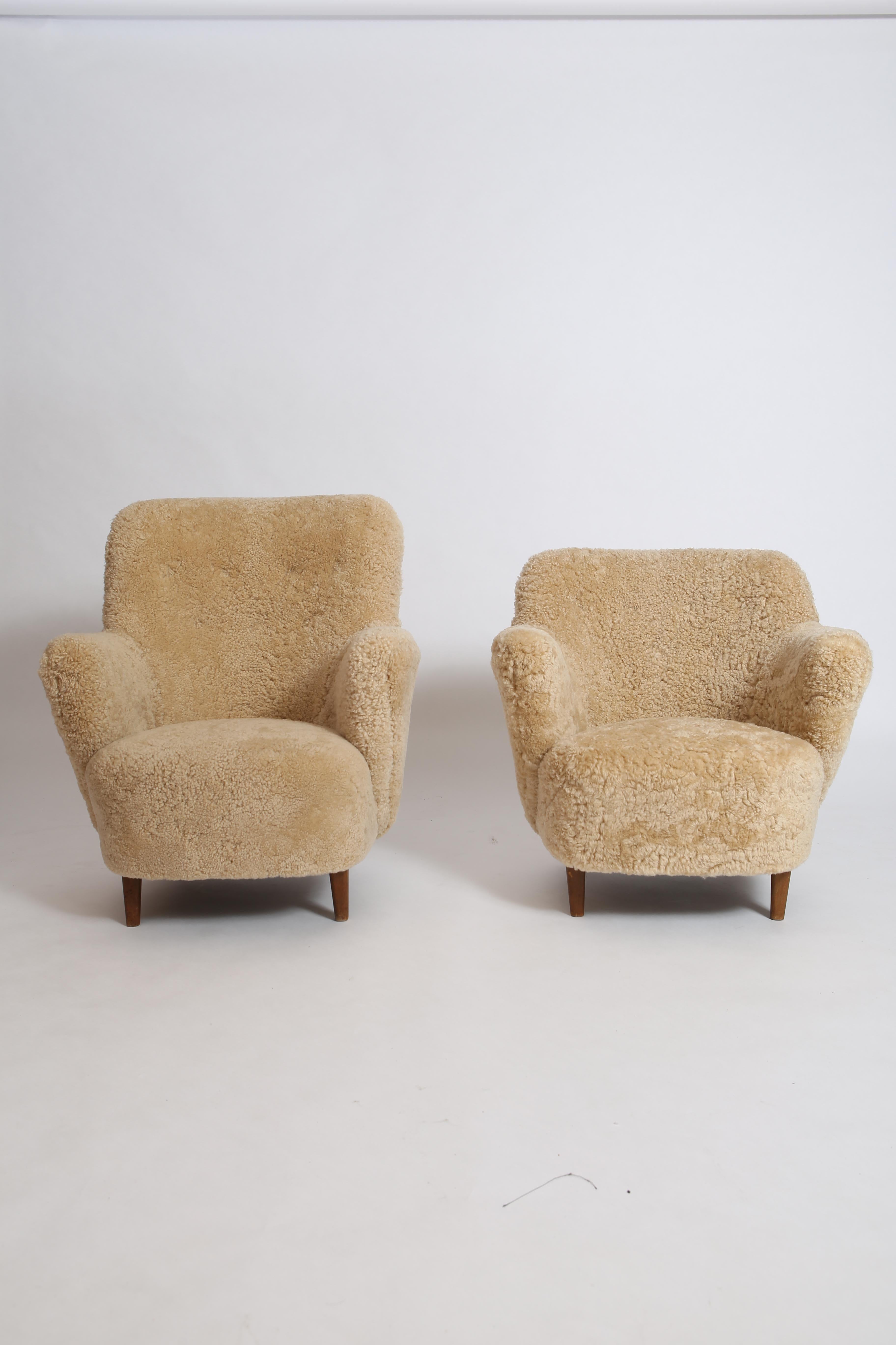 Wonderful matched “his and hers” pair of Danish Cabinetmaker armchairs freshly upholstered in natural sheepskin. 
Elegant lines, these chairs are beautiful from different angles-finished with button-tufted backrests, hand-tied springs and all new