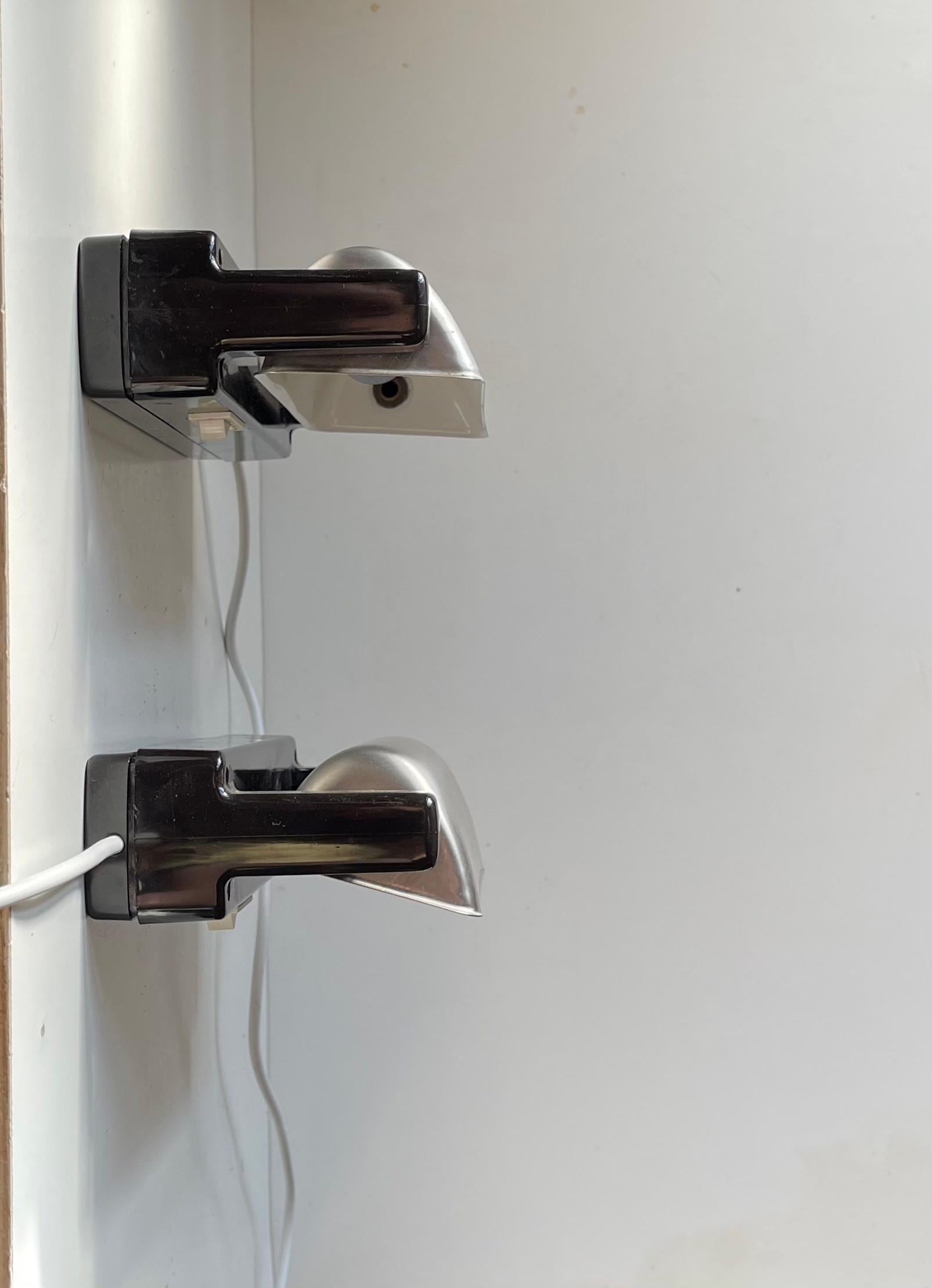 Un par de apliques náutico-marítimos con pantallas giratorias de acero inoxidable. Han servido como luces de cama de camarote a bordo de un barco estatal noruego hasta hace poco. Posiblemente fabricado por Lyfa o Nordisk Solar Co. en Dinamarca. Las