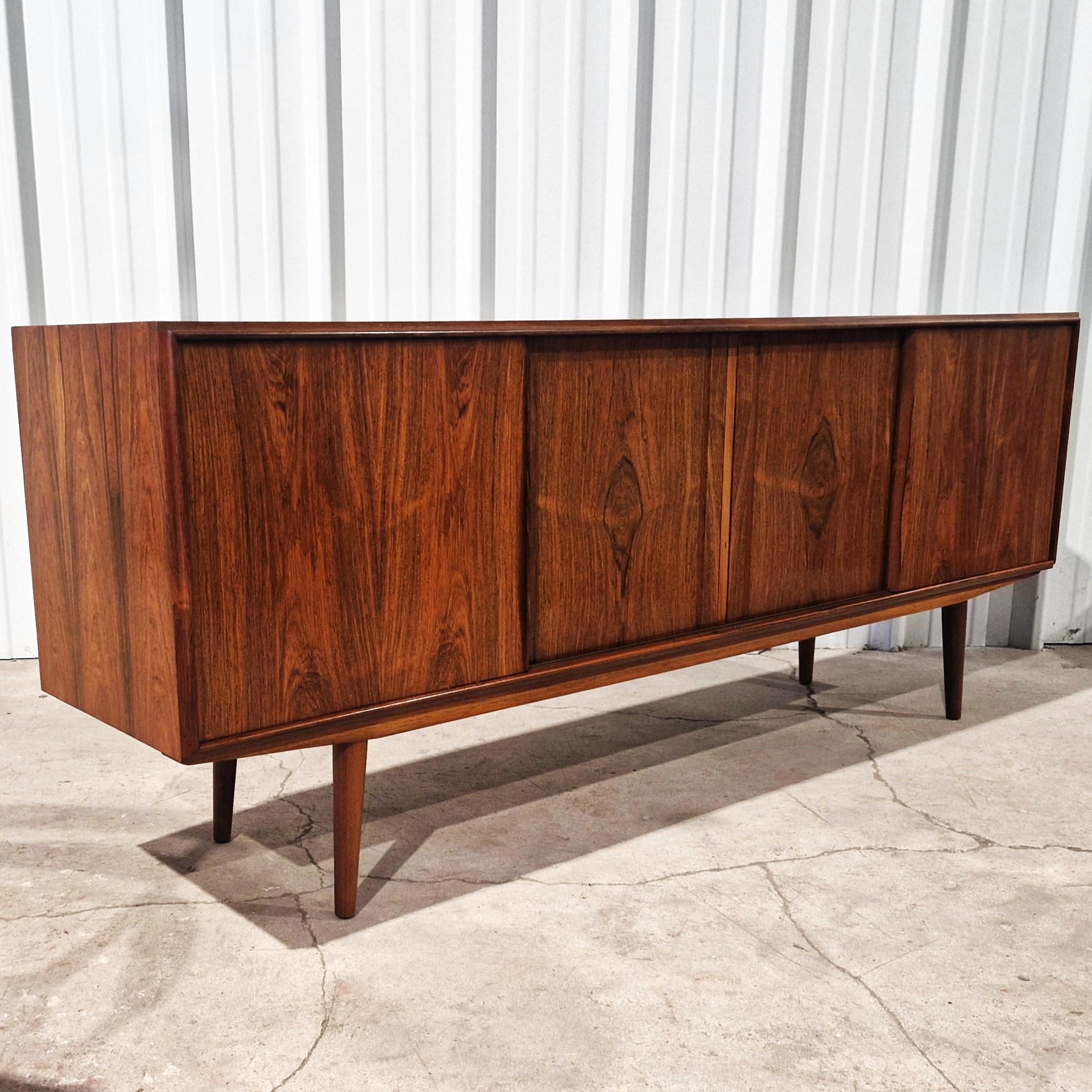 Elegant Scandinavian sideboard by E.W. Bach for Sejling Skabe publisher, Denmark, 1960s. This piece of furniture, set on compass legs, opens with 4 sliding doors revealing ample storage space. Very good condition, with very slight signs of use.