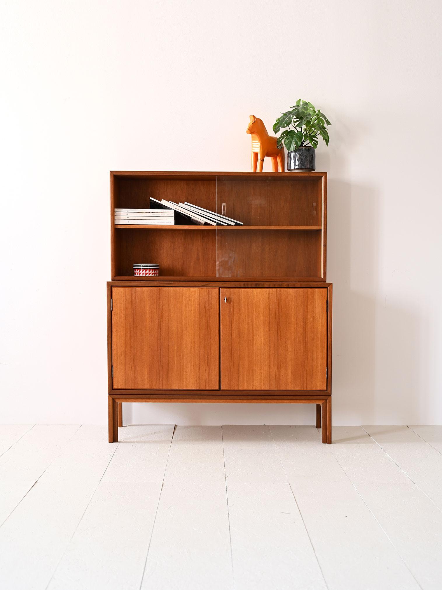 Small 1960s sideboard made of teak and glass.

A piece of furniture with an original shape that, thanks to its small size, can be placed in a kitchen or hall with a small space.
Consists of a low cabinet with hinged doors equipped with a lock on