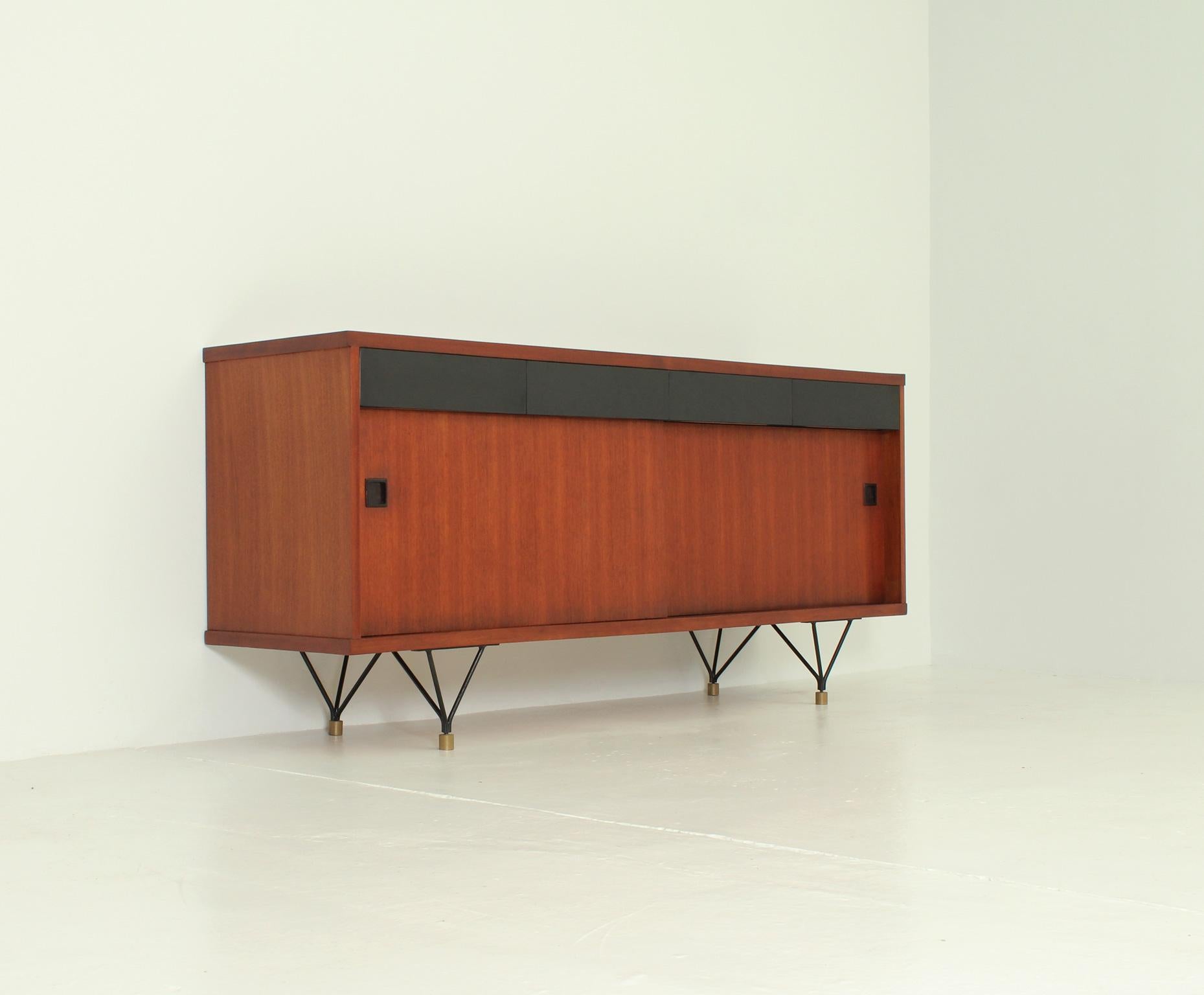 Scandinavian sideboard from 1950's. Teak wood with two storage spaces with shelves and sliding doors and four drawers with black laminated front, black lacquered metal and brass bases.