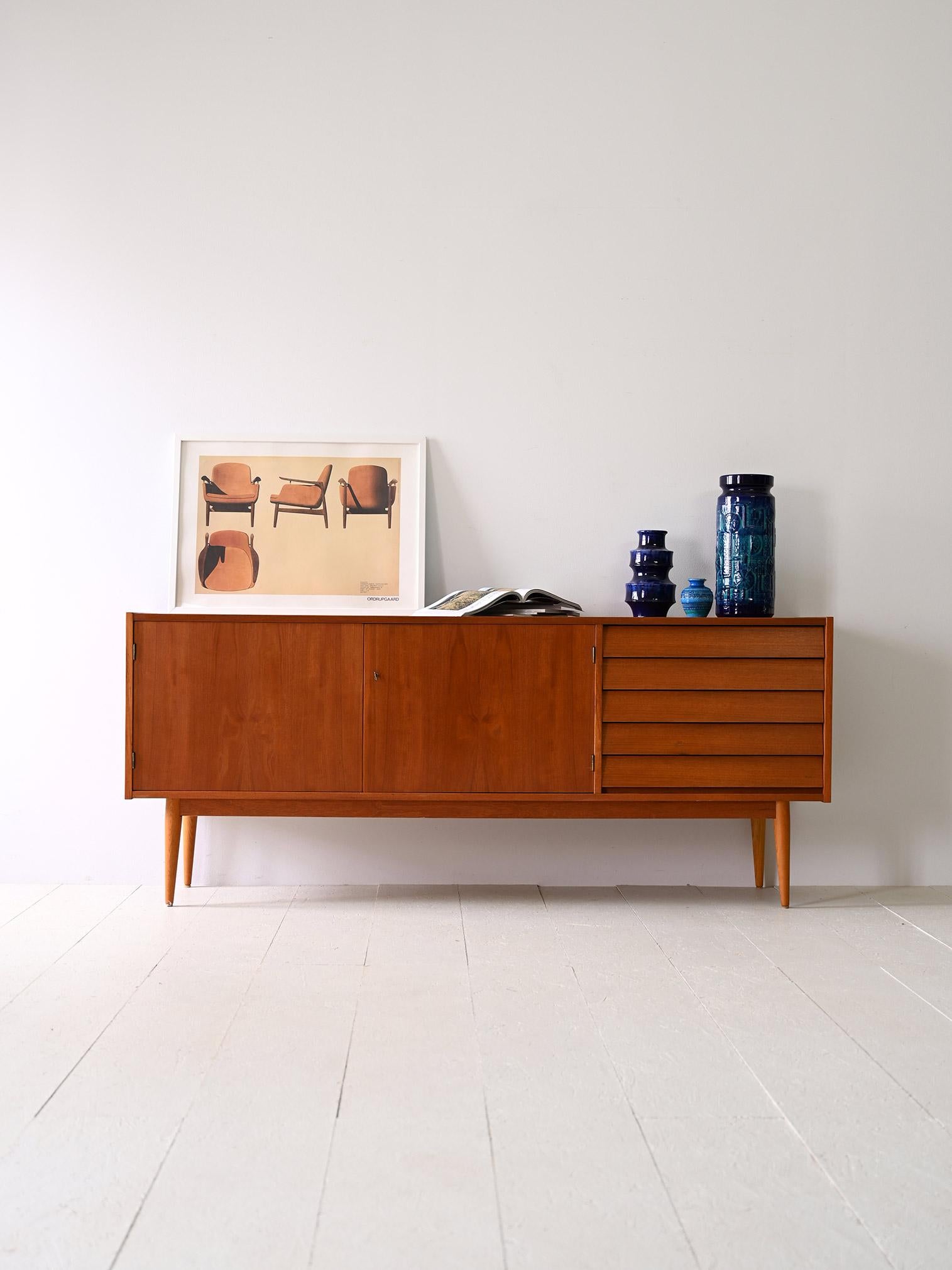 Scandinavian sideboard in original vintage teak.

This teak sideboard is an icon of elegance and simplicity, ideal for any room in your home. With five drawers placed on the right side and large hinged doors on the left side, it offers practical