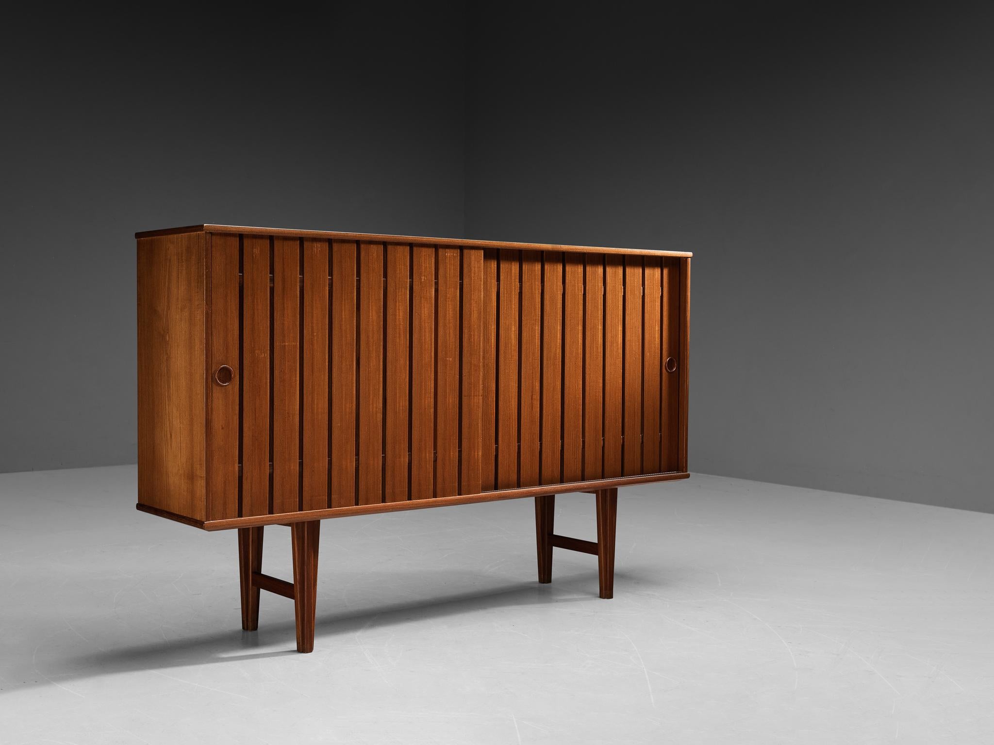 Sideboard, teak, Scandinavia, 1960s

This very elegant and slender sideboard is made in the 1960s in Scandinavia. The two slatted sliding doors in front both have a recessed handle, keeping a clean aesthetic. The interior offers plenty of storage