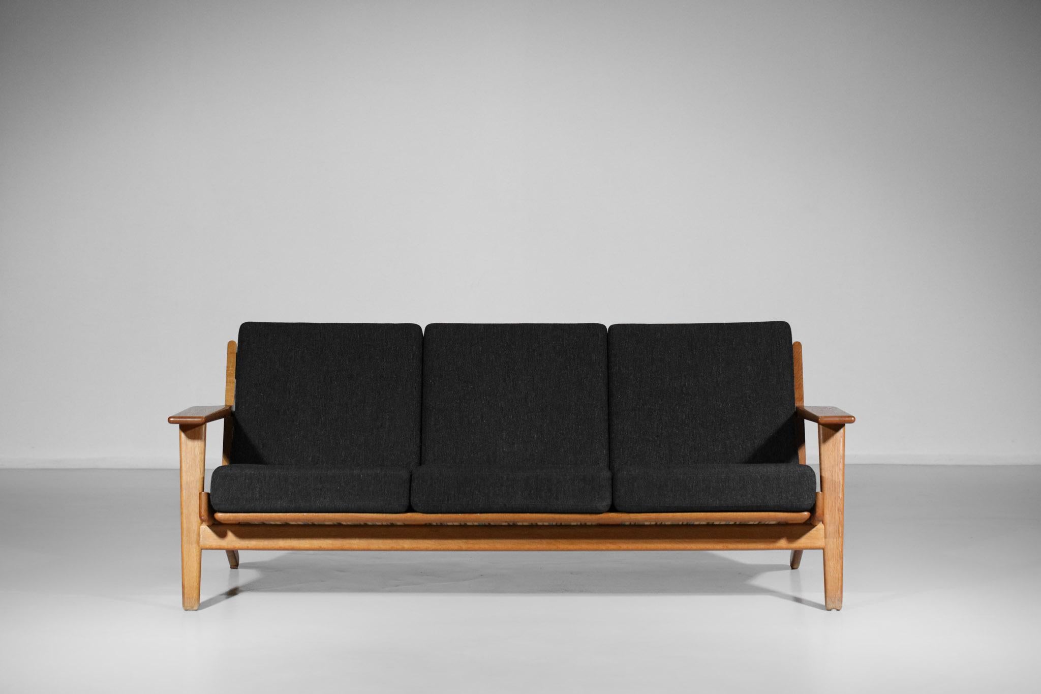 Scandinavian sofa GE 290 by the famous Danish designer Hans Wegner, published by GETAMA in 1955. Solid oak frame, sloping legs and slightly sloping backrest optimize the seating comfort typical of this 3-seater model. Original cushions