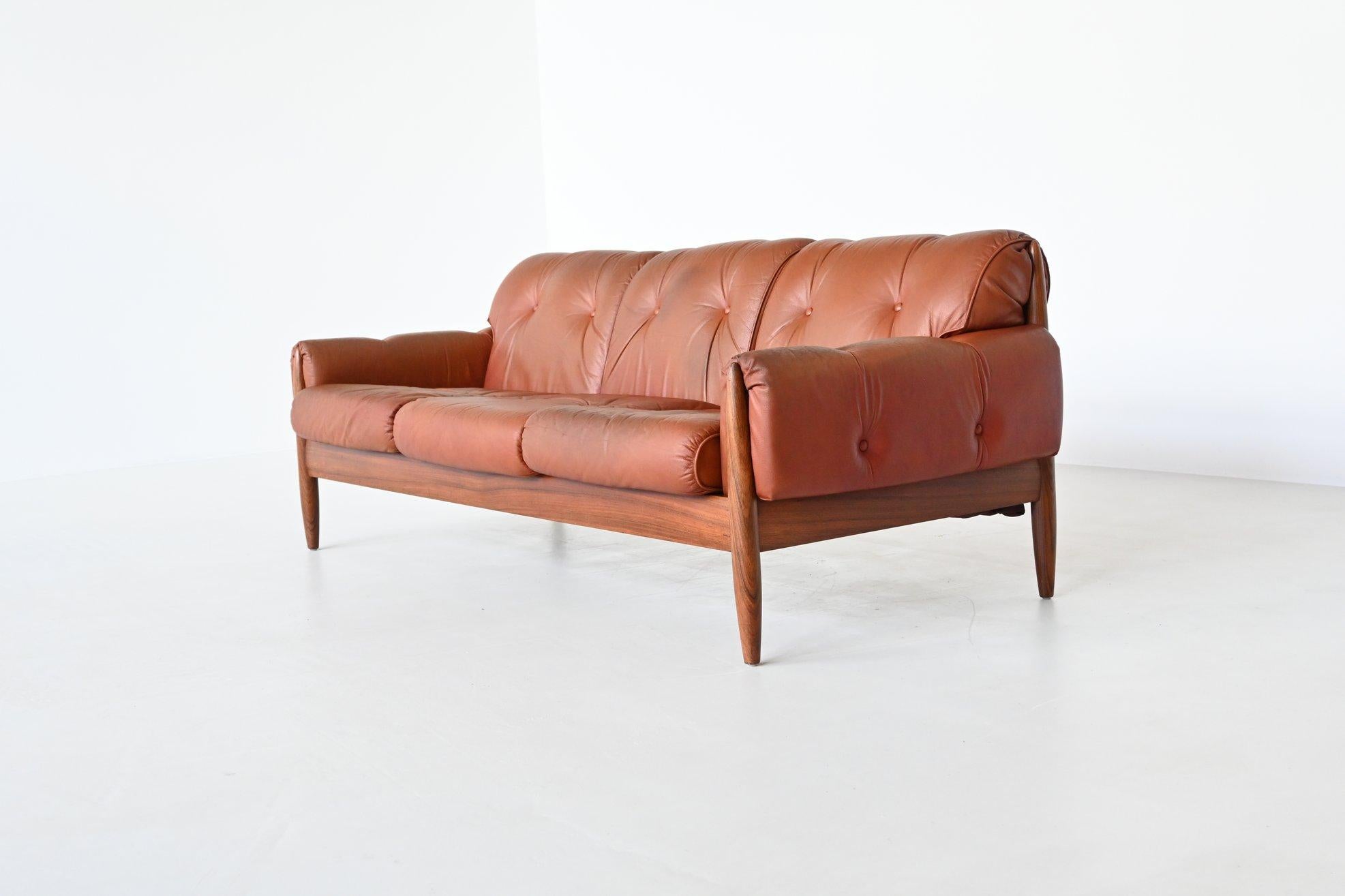 Beautiful shaped Scandinavian lounge sofa, Denmark 1960. This unique three-seater sofa has a solid rosewood frame with cognac leather cushions. Very nice details are the well-crafted tapered legs and high quality original leather. This amazing sofa