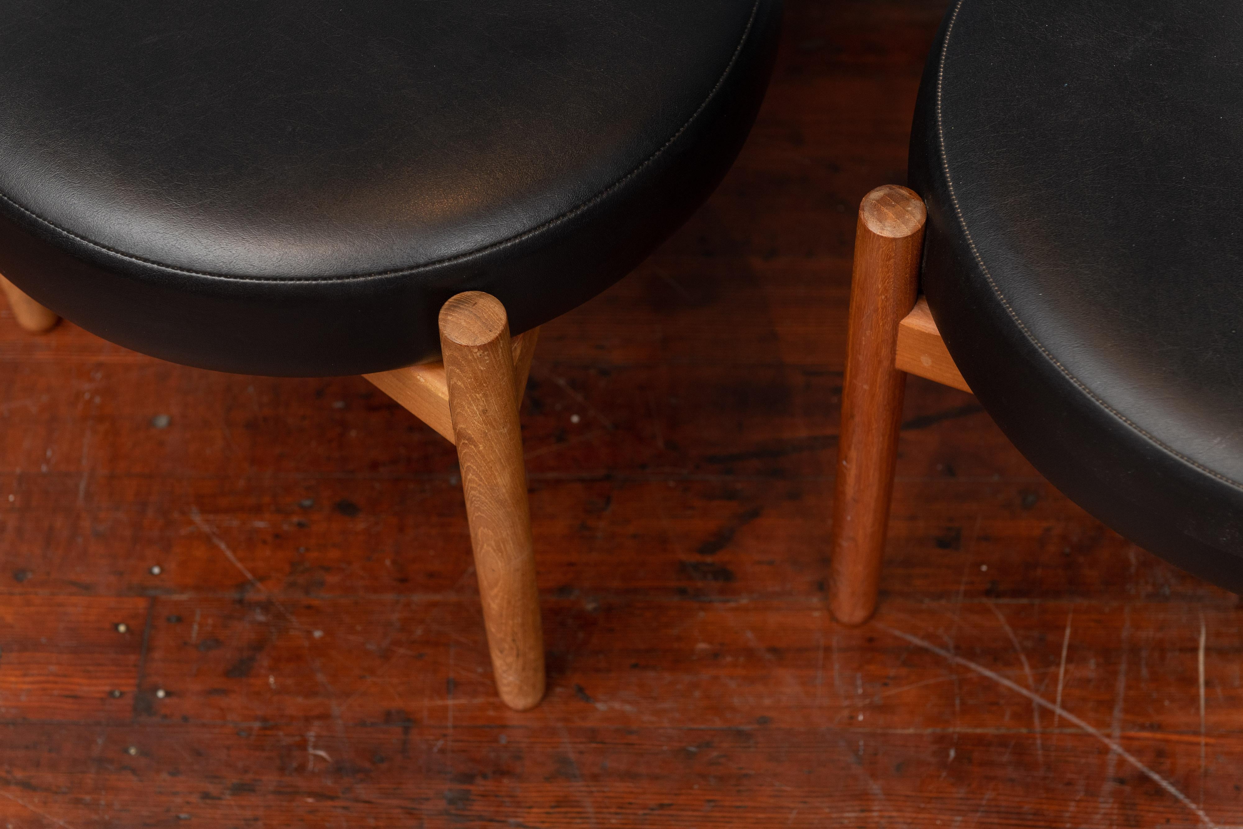 Scandinavian three legged teak stools designed by Hugo Frandsen for Spottrup, Denmark. Original black vinyl upholstery, labeled.