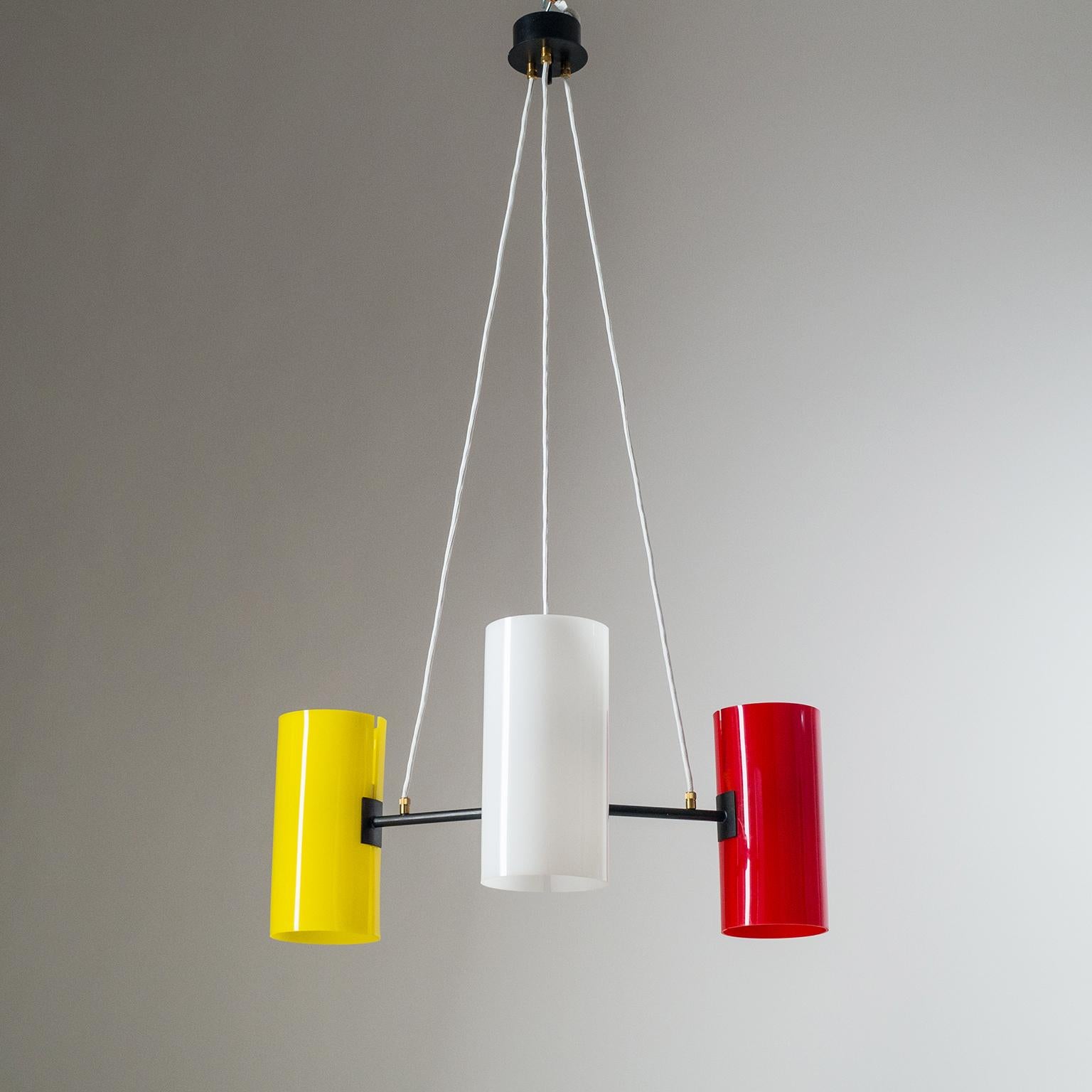 Lustre scandinave minimaliste à suspension avec des abat-jour en acrylique coloré. La quincaillerie est en laiton laqué avec une pièce centrale en bois laqué. Chaque bras se termine par un grand diffuseur en acrylique avec une douille E27 et un