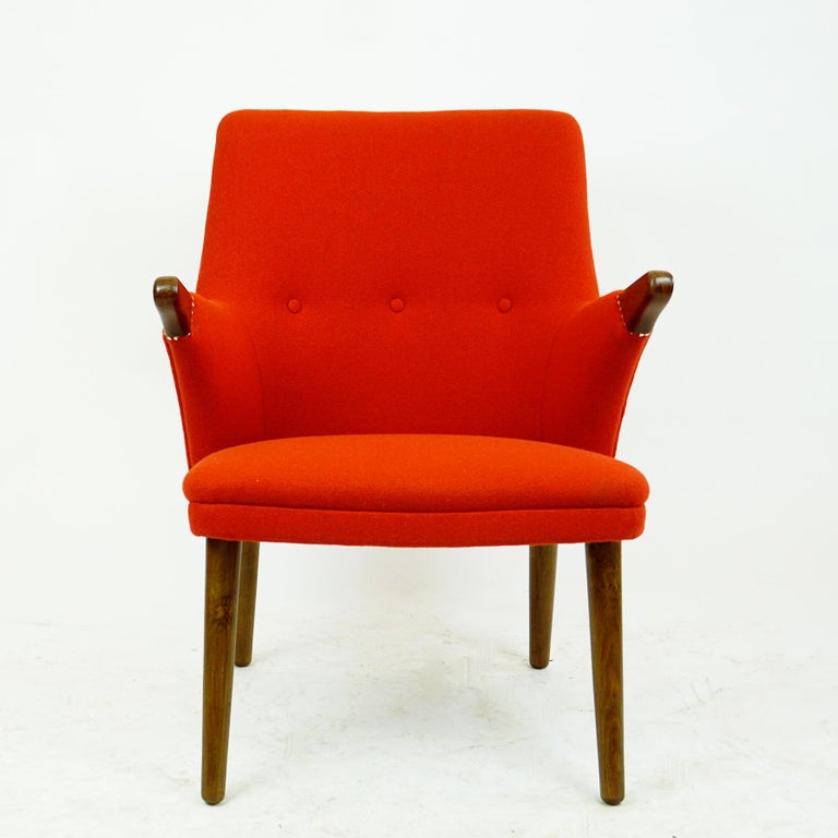 This charming Scandinavian Modern armchair echoes the design of Hans Wegners famous Papa Bear chair as a smaller version. It is designed by Svend Skipper and produced in Denmark 1960s and features renewed orange red Kvadrat Fabric upholstery with