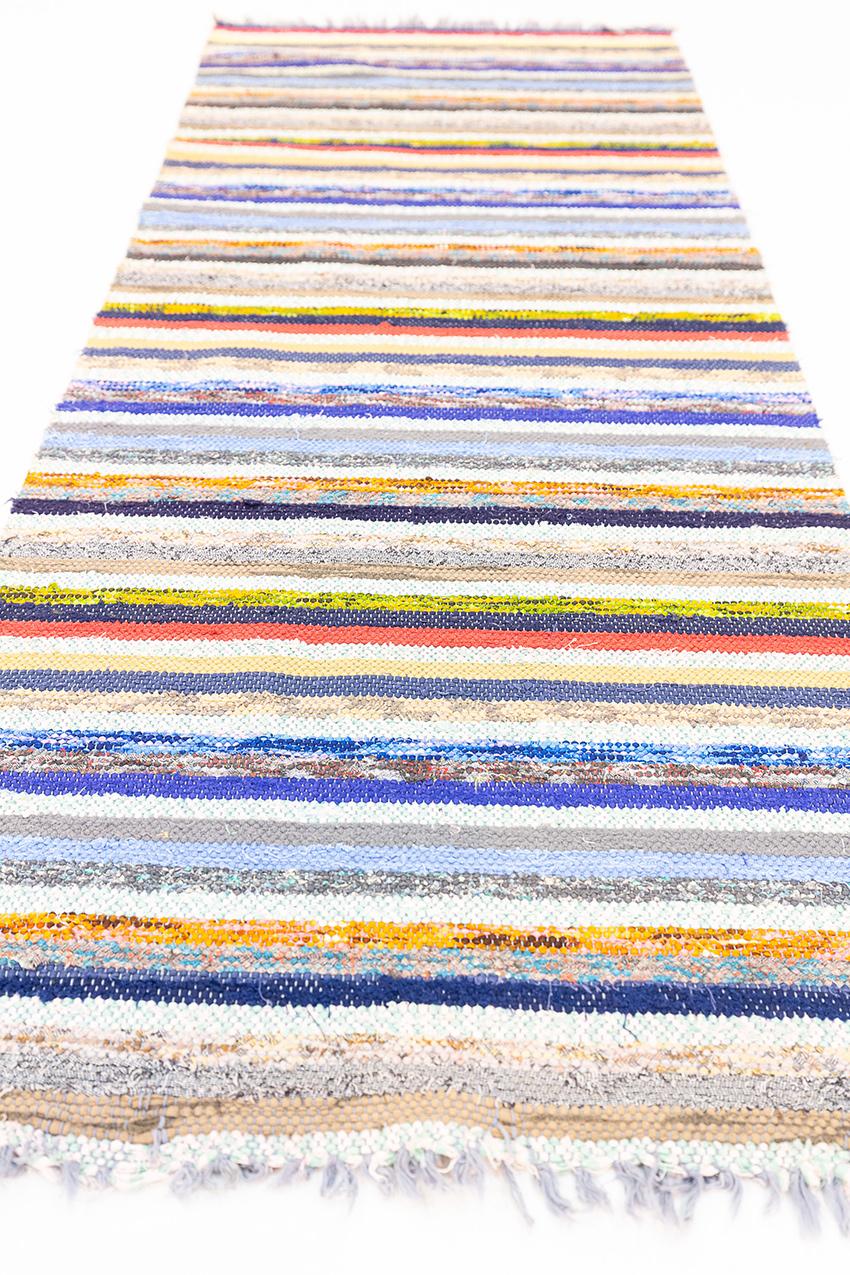 Questo kilim svedese multicolore è un pezzo davvero notevole che si distingue per le sue caratteristiche uniche e speciali. Intrecciato a mano con una meticolosa maestria artigianale, mostra una vibrante tavolozza di colori che si fondono