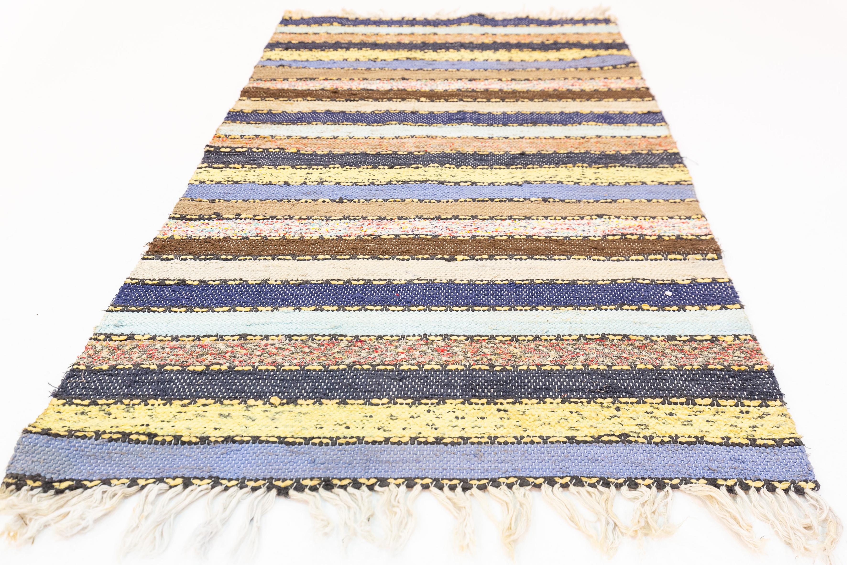 This piece is a Swedish flatweave rug, commonly known as a 'trasmatta', showcasing the traditional and resourceful craftsmanship of Scandinavian textile art. The rug features a series of horizontal stripes in a muted yet diverse palette that