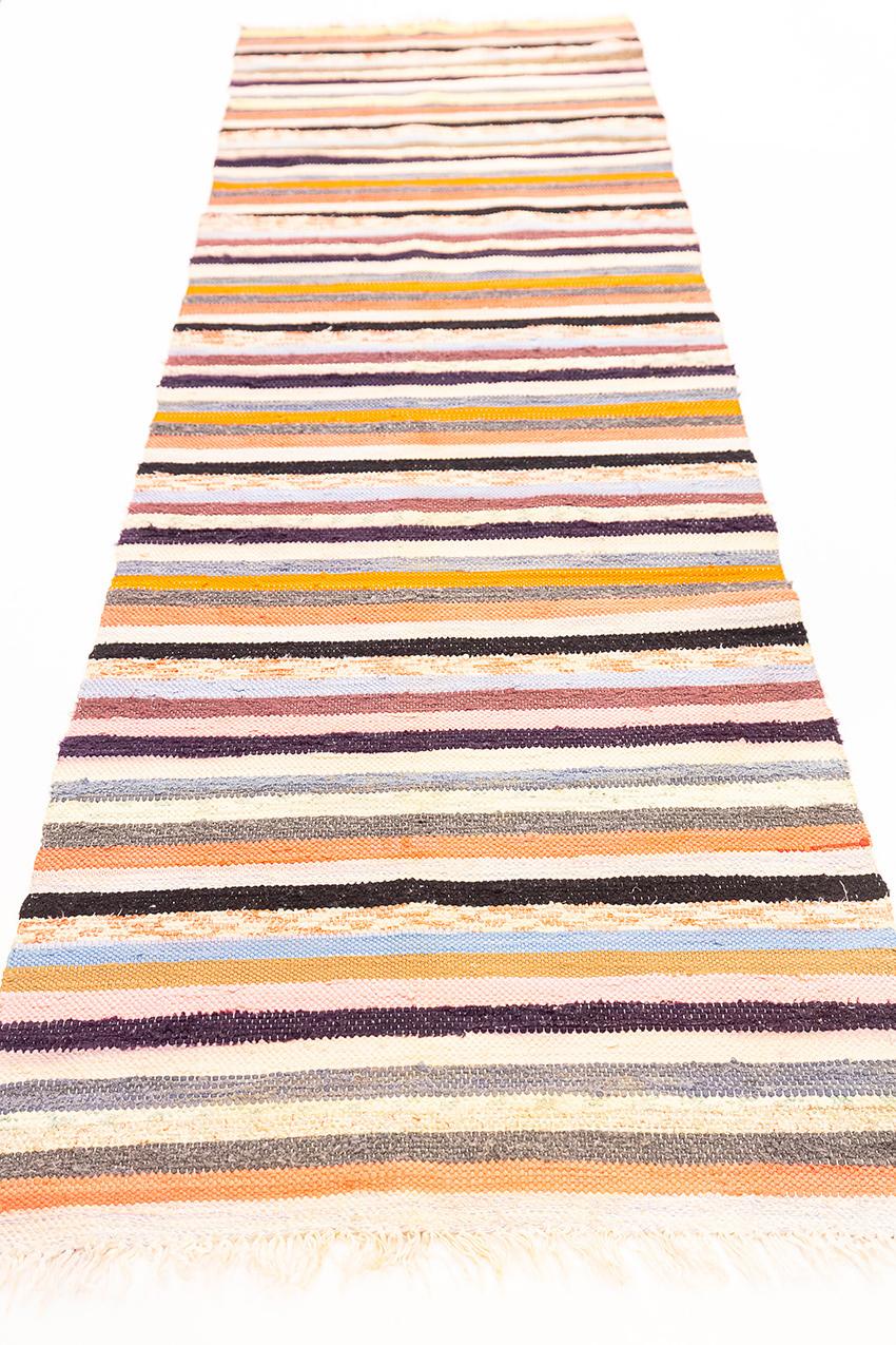 This Swedish kilim boasts a soft multi-color palette and features a charming stripe design that adds a touch of contemporary elegance to its overall aesthetic. The colors used in this kilim are delicately muted, creating a soothing and tranquil