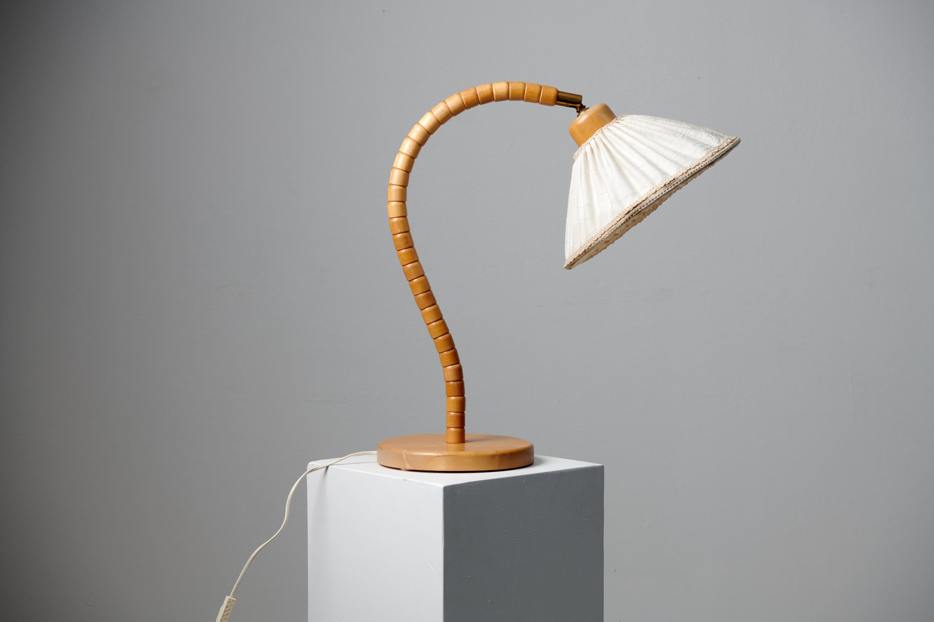 Scandinavian modern table lamp by Markslöjd Kinna Sweden, with a makers mark underneath. The lamp is from the 1960s and has a frame in birch. The end connecting to the lamp shade is in brass and the shade itself is the original linen. The lamp has