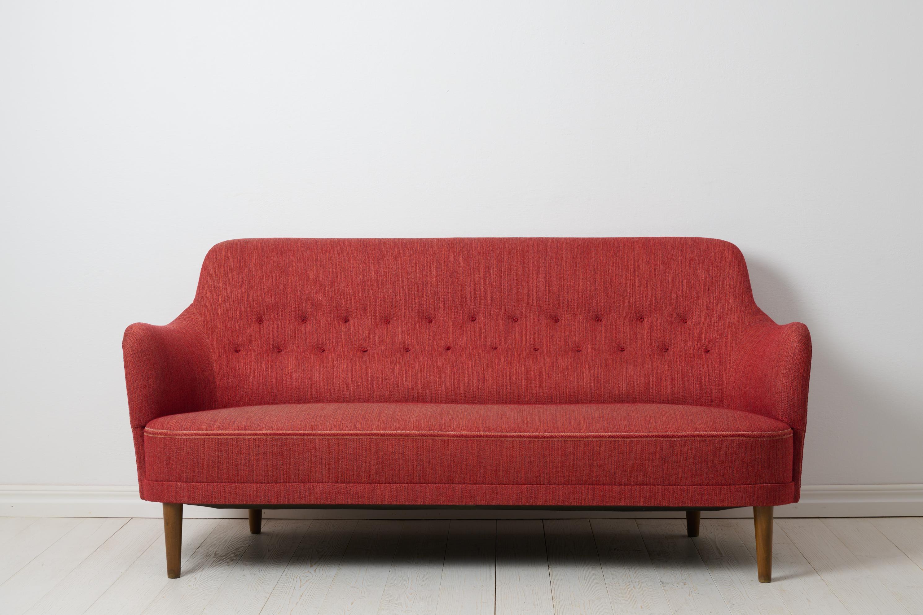 Scandinavian modern sofa “Samsas” by Carl Malmsten for O.H Sjögren in Tranås. The sofa is a mid-century modern classic with a solid pine frame and red toned upholstery. The sofa, often regarded as the quintessential embodiment of Malmsten’s style,