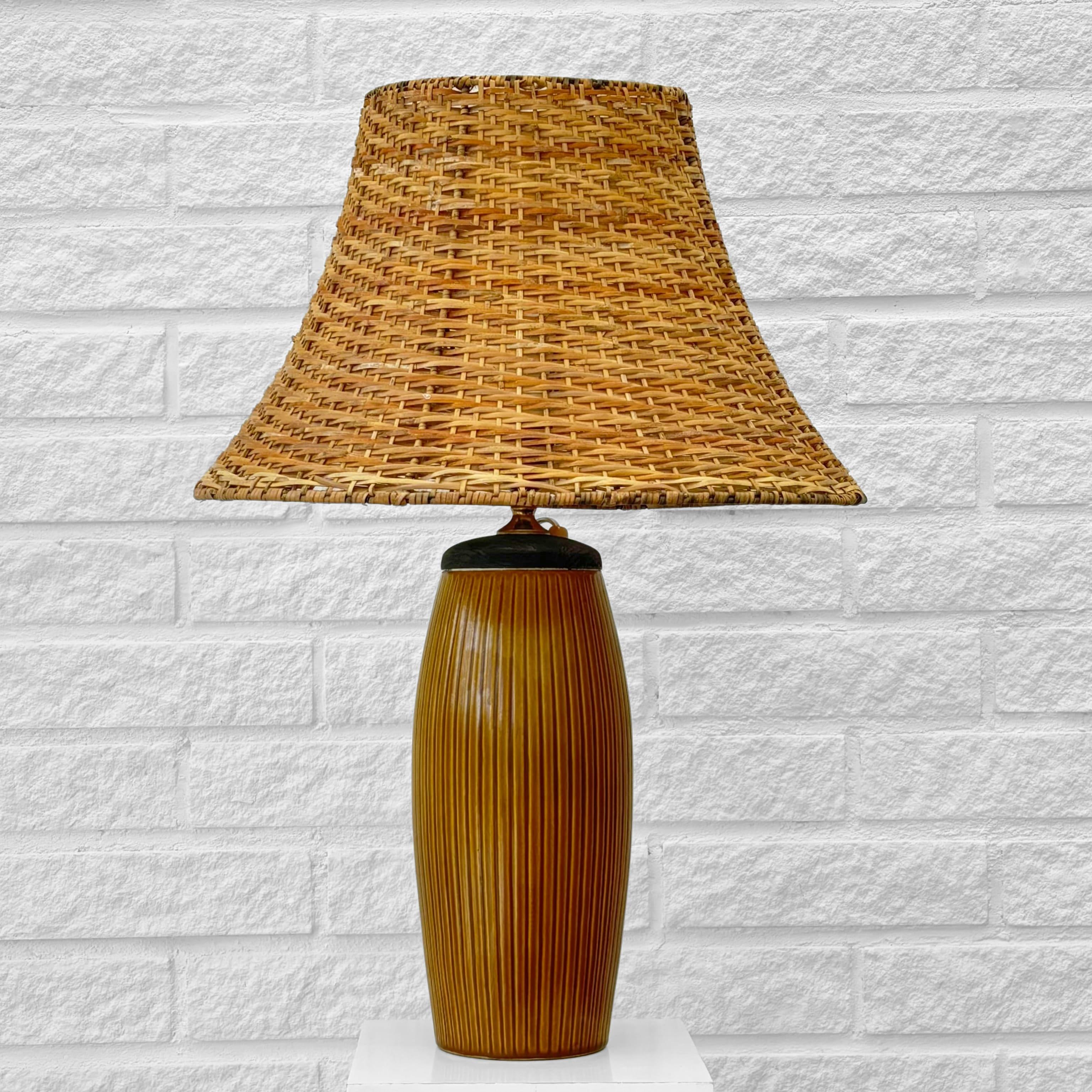 Una grande e imponente lampada da tavolo svedese degli anni '40, realizzata in ceramica smaltata con dettagli in ottone e pino mordenzato. Firmato sotto dal produttore di ceramiche Bo Fajans. La base in ceramica dalla forma morbida presenta strisce