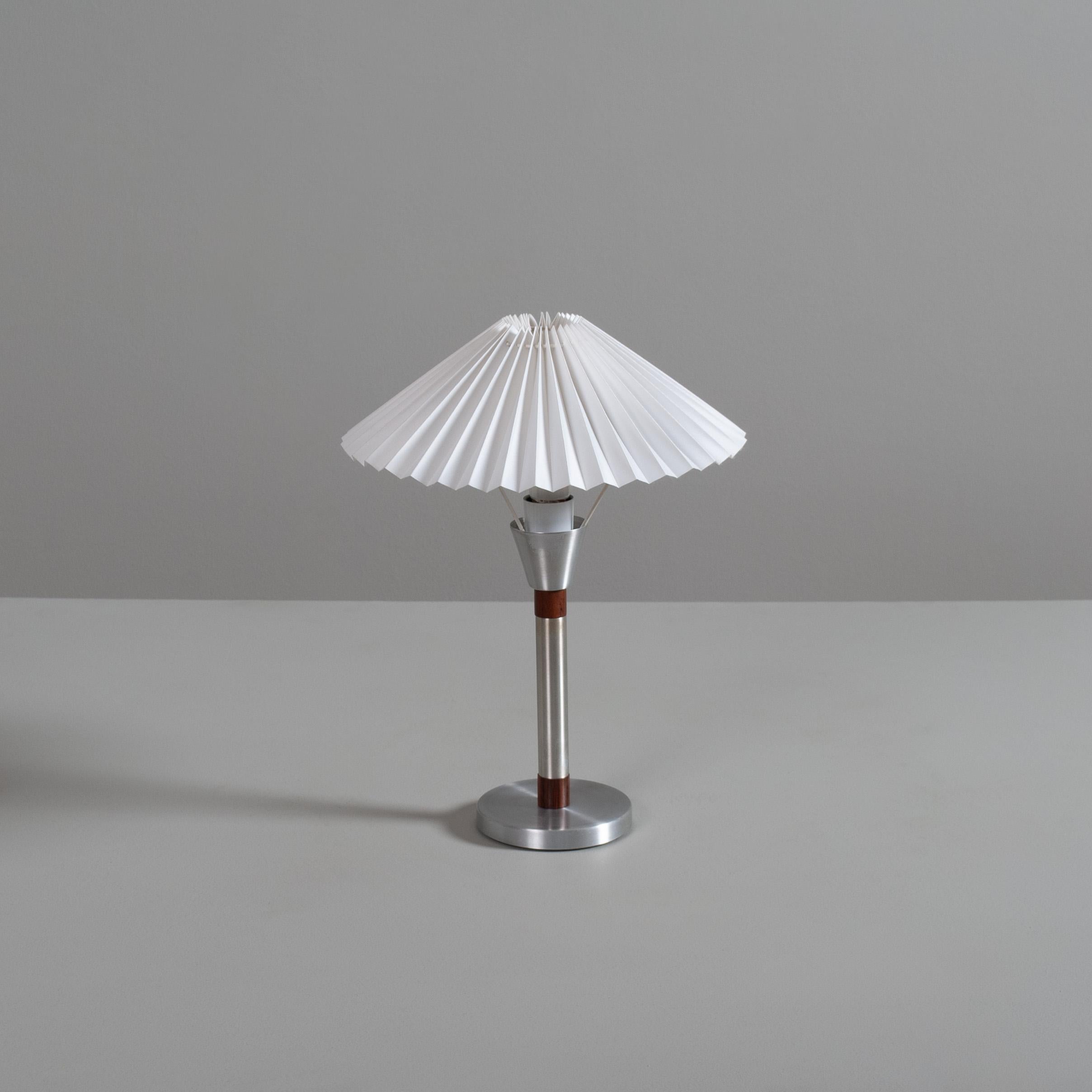 A very sweet table lamp of the early 1950's. Aluminium interspersed with teak. Classic pleated shade. On/off button to stem.
Can be used internationally.
Produced in Denmark.