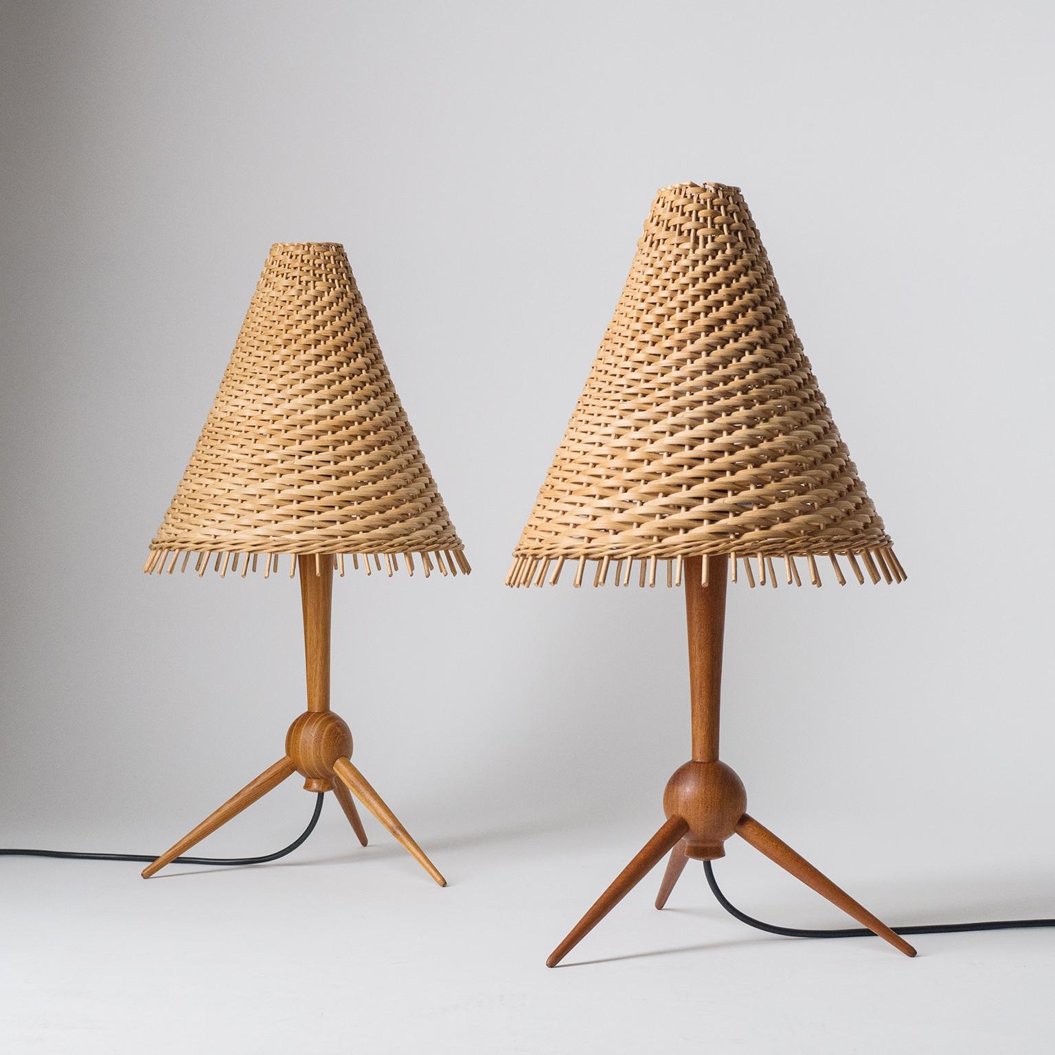 Rare pair of Scandinavian tripod table lamps in teak with rattan shades. Lovely delicate design with tapered teak stem and legs and organic rattan shades that sit atop a wireframe which is mounted onto the bulb. Fine original condition with minor