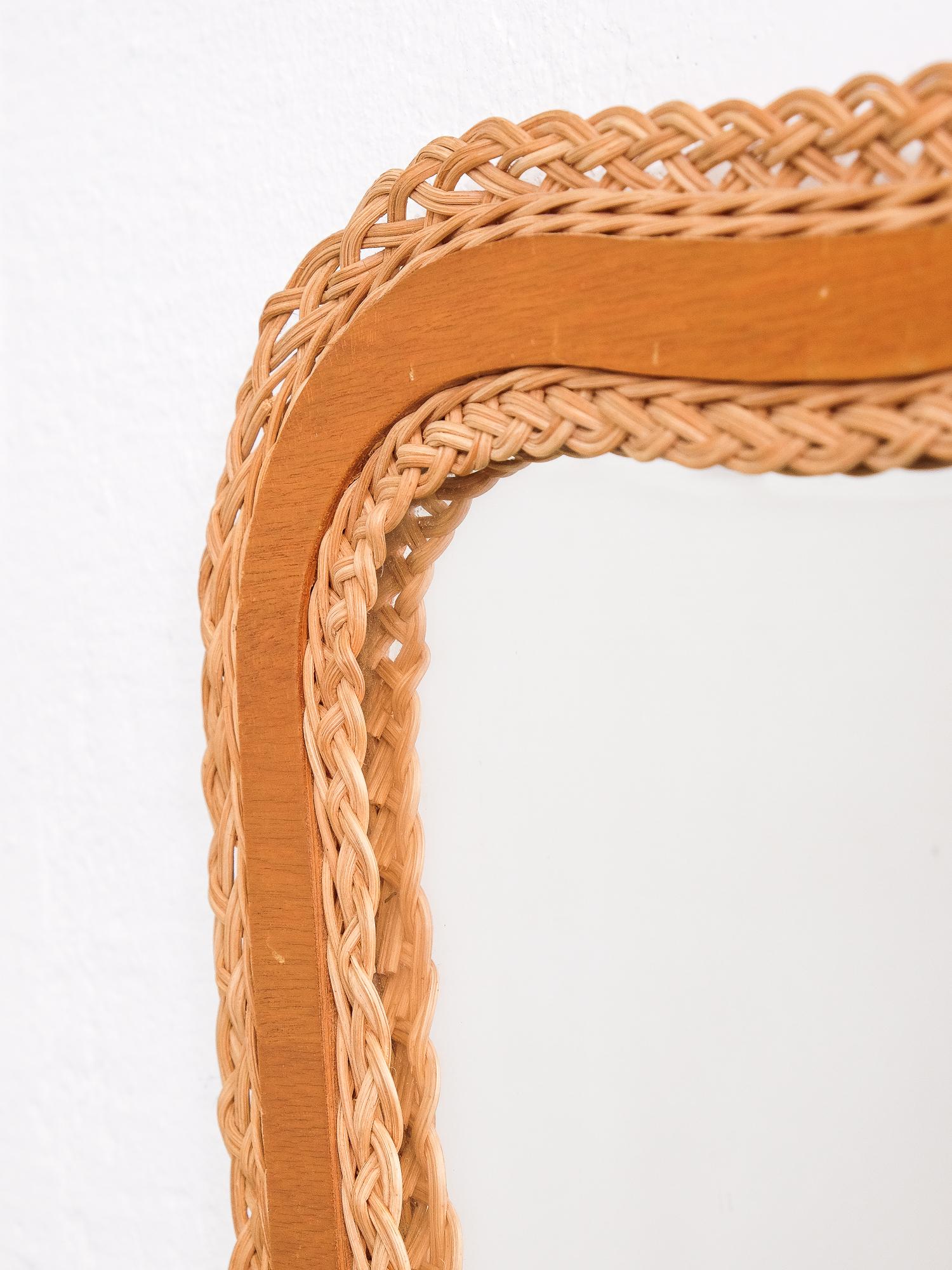 A wall mirror with its original mirror glass, teak and braided rattan frame. Produced in Sweden, 1950s.