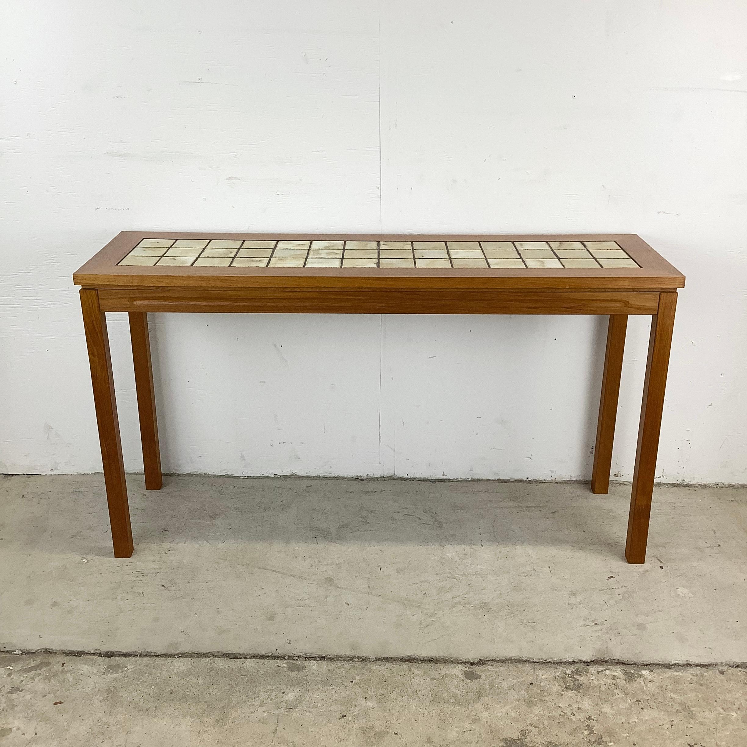Elevate your living space with this stunning teak console table with tile inlay top, a wonderful example of vintage Scandinavian design. With its sleek lines and warm teak wood, this table is a quintessential example of the timeless appeal that