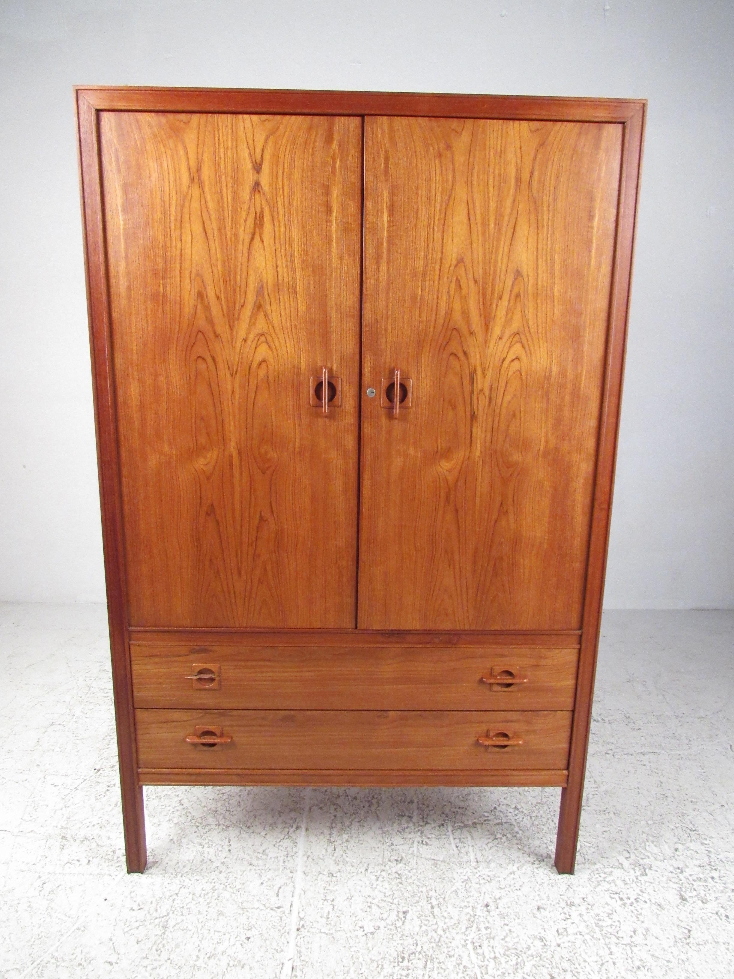 This stylish Scandinavian Modern armoire by J Clausen for Brande Mobelfabrik features exquisite teak construction, dovetail joints, and unique carved handles. Substantial piece of quality Mid-Century Modern furniture, perfect for bedroom