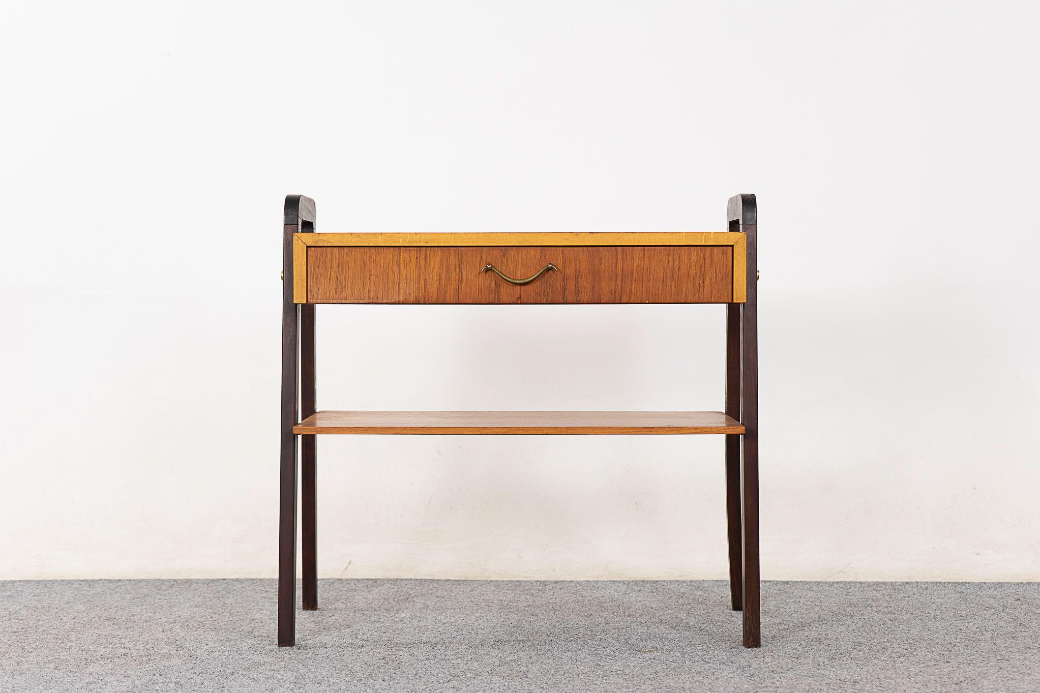 Teak mid-century bedside table, circa 1960's. Beautifully veneered case rests on contrasting black splayed legs. Slim drawer with darling metal handle and a handy lower shelf! 

Please inquire for international and remote shipping rates.