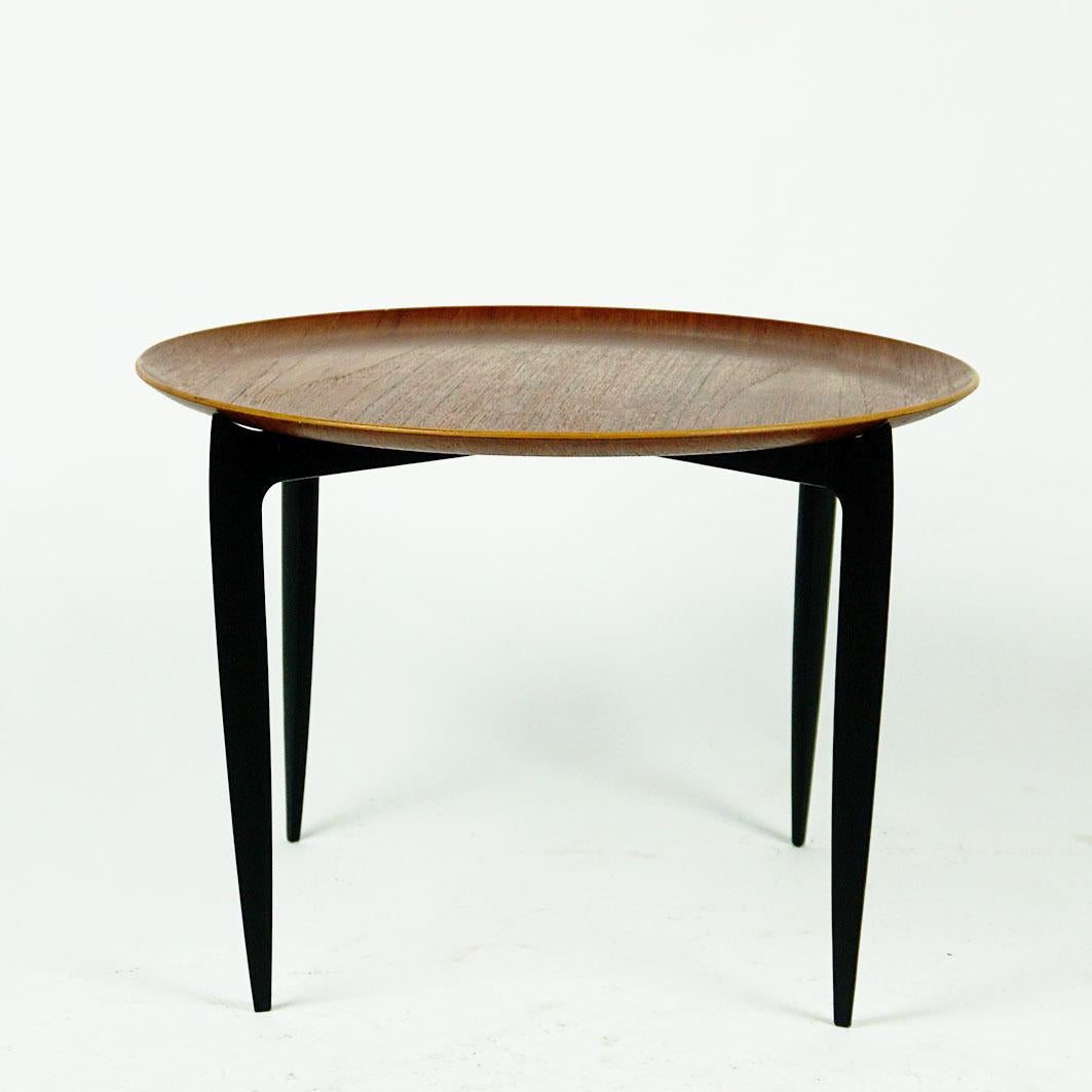 This Iconic Scandinavian Modern circular foldable teak coffeetable table with removable tray top has been designed by Svend Åge Willumsen & Hans Engholm for Fritz Hansen, Denmark 1950s, Model 4508.
it features a black lacquered foldable base and a