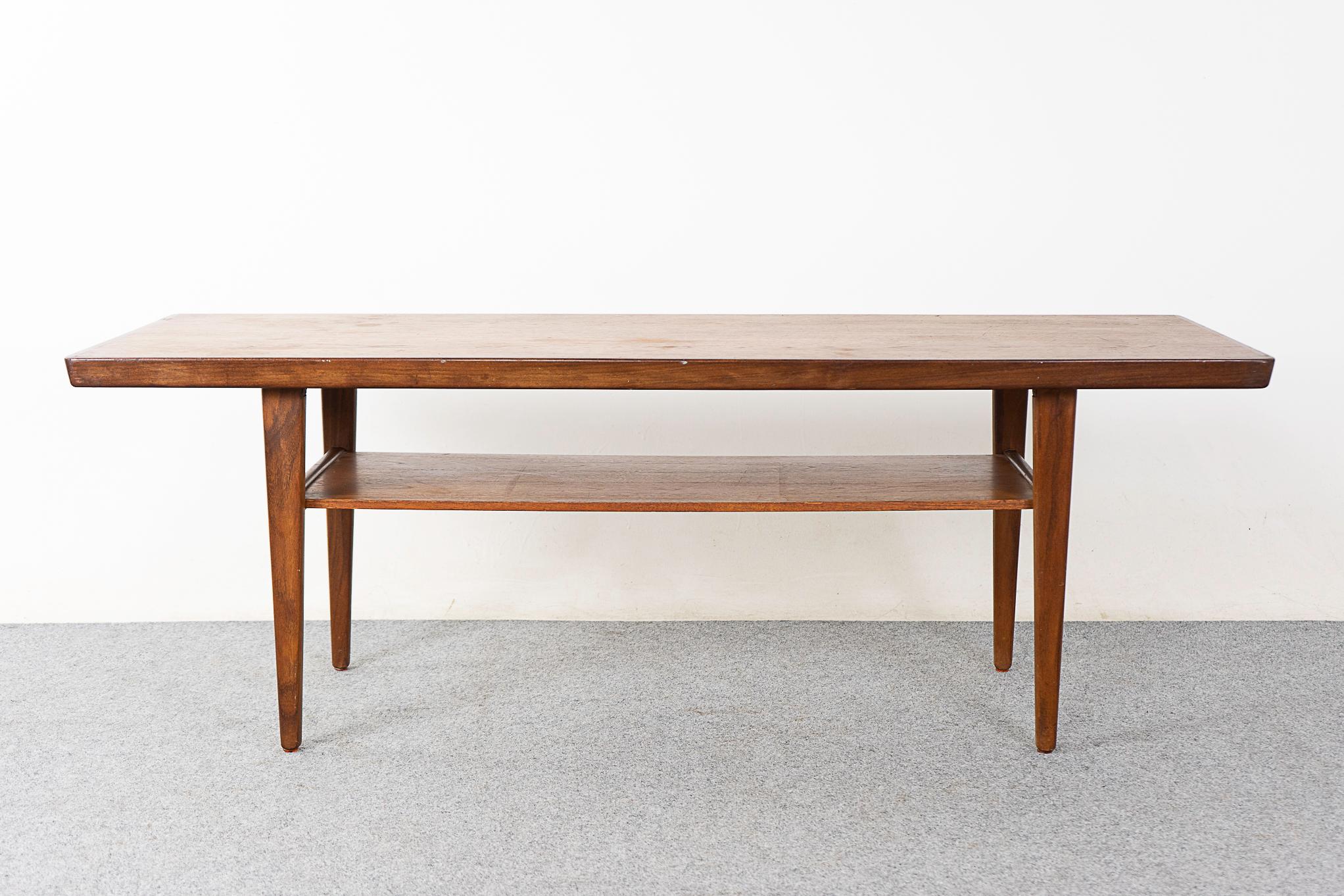 Teak mid-century coffee table, circa 1960's. Top surface has beautiful book matched veneer, angled solid wood edge and elegant legs. Convenient lower shelf, hide away clutter!

Please inquire for remote and international shipping rates.
