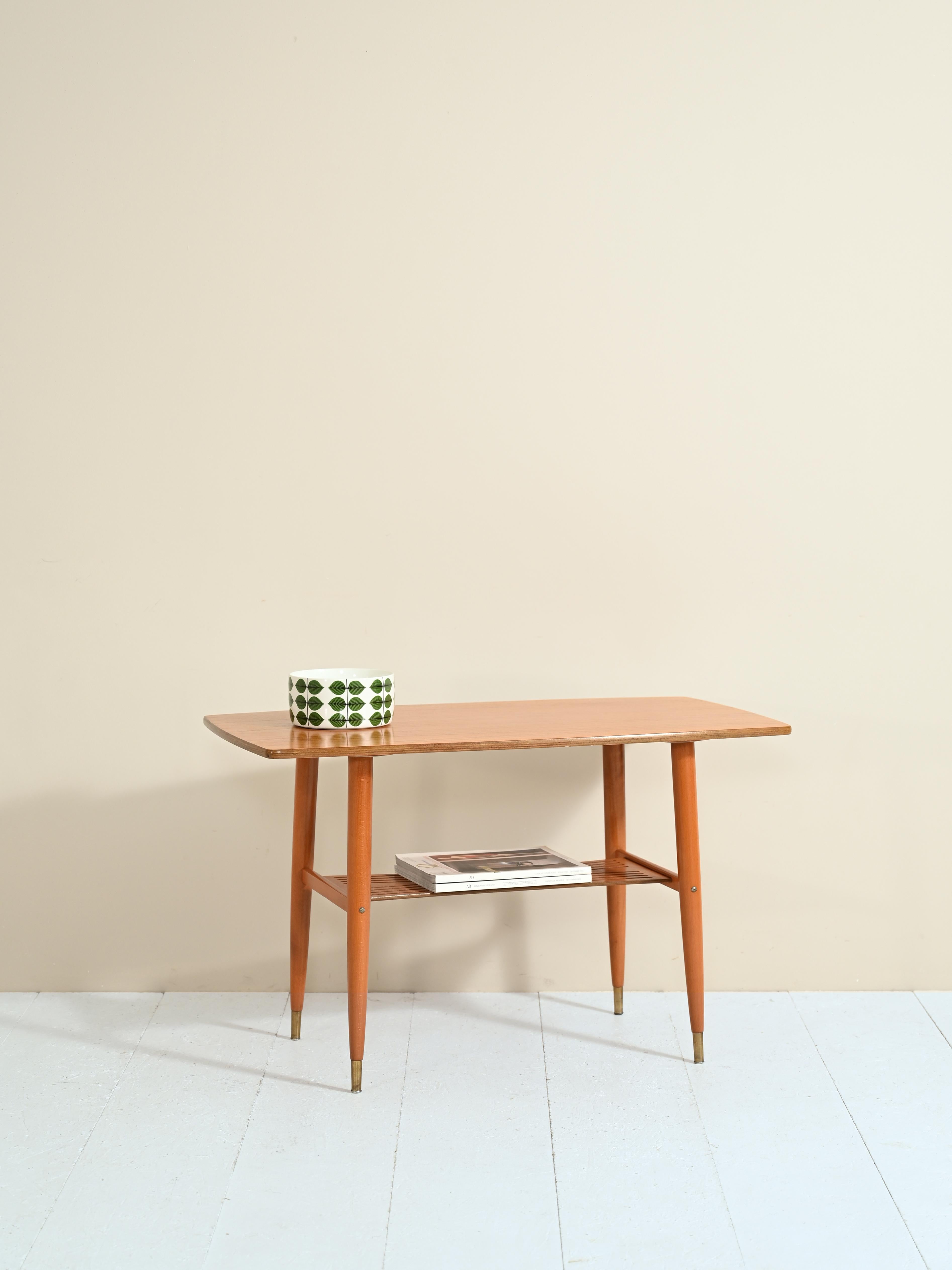 Vintage coffee table with magazine shelf.

The clean and minimal lines follow the Nordic tradition of combining aesthetics and functionality.
This small-sized coffee table can be used as a bedside table, and thanks to the presence of a second